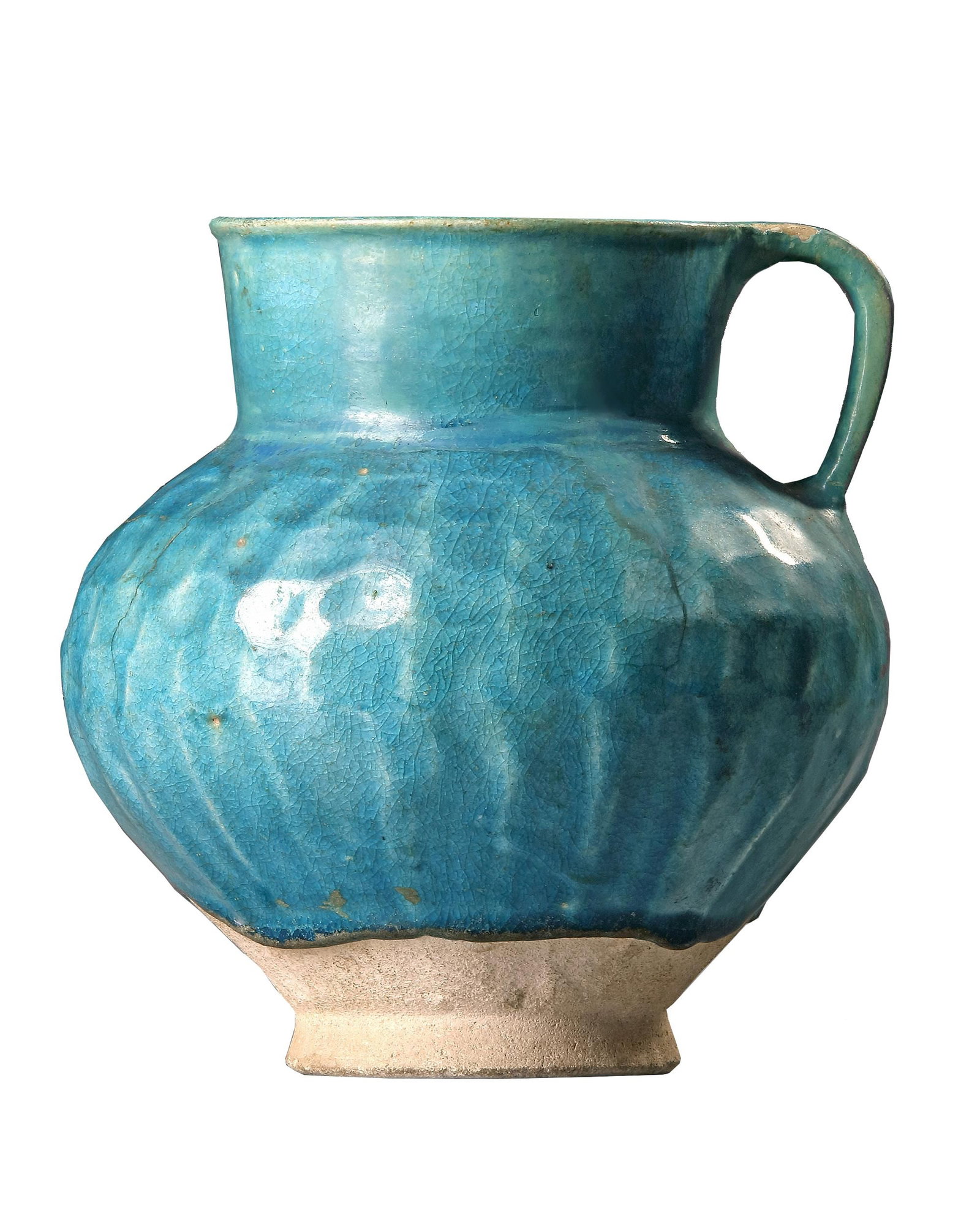 A TURQUOISE BLUE GLAZED POTTERY JUG, PERSIA-KASHAN, 12TH CENTURY: A kashan jug with rounded ribbed body and cylindrical neck standing on a small unglazed foot, covered with a turquoise glaze. Height: 18 cm. The rim and handle with restoration. PROVENANCE Private col
