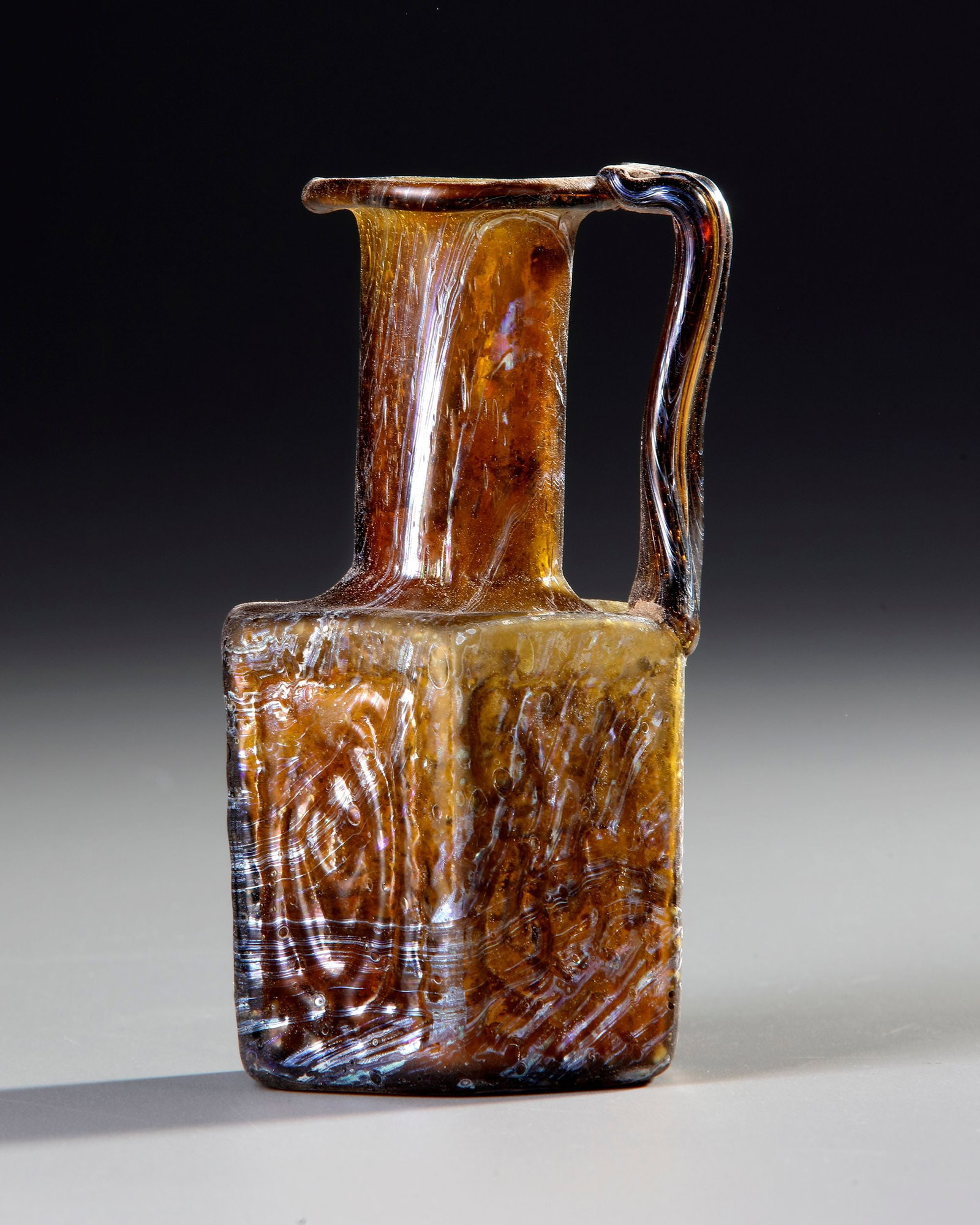 AN AMBER MOLDED GLASS JUGLET, EASTERN MEDITERRANEAN, 1STâ€“3RD CENTURY AD (1 of 3)