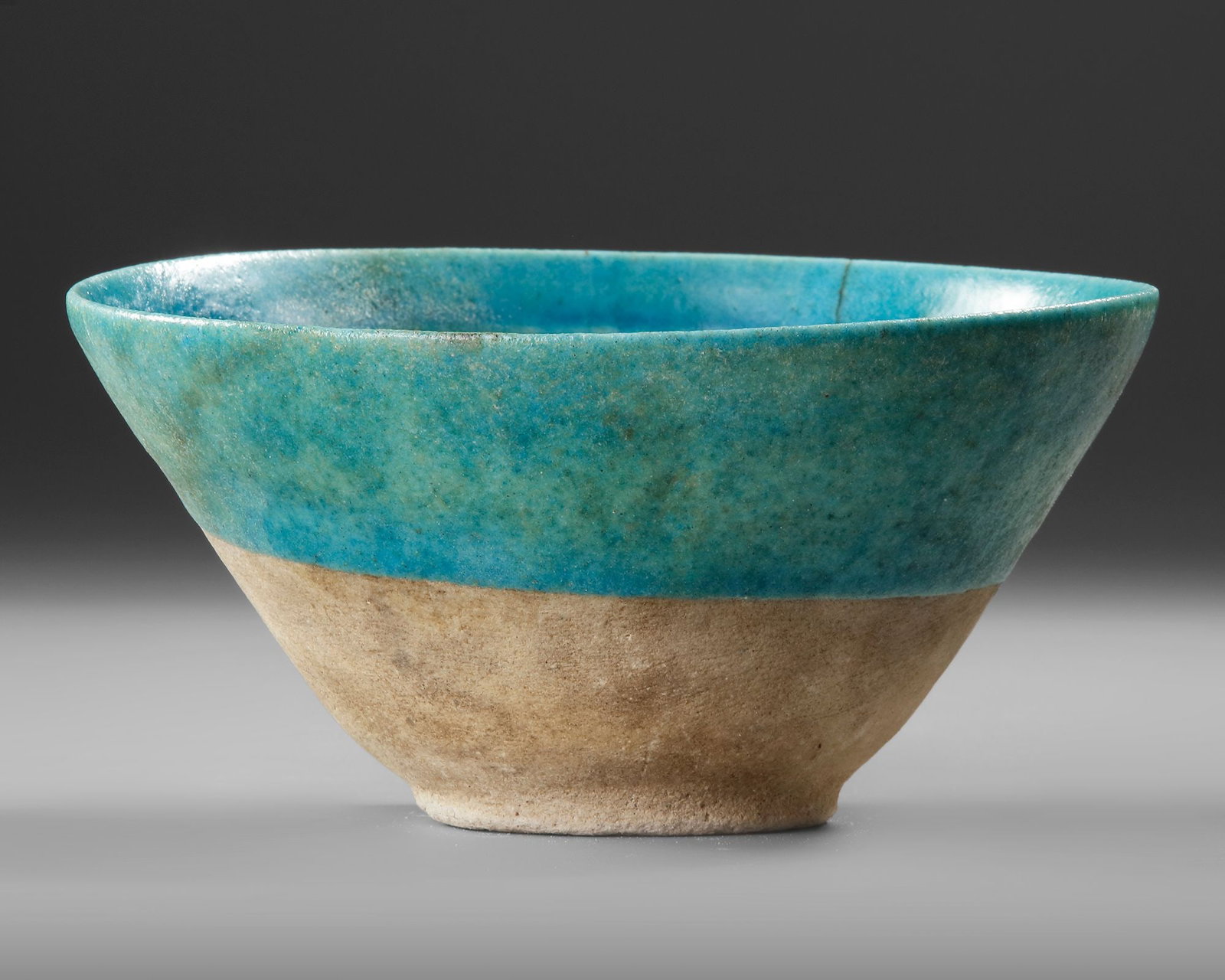 A BAMIYAN MONOCHROME MOULDED POTTERY BOWL, PERSIA, 12TH-13TH CENTURY: Of conical, rounded form on short feet, in a turquoise glaze, the moulding consisting of a central interlace motif and symmetrical designs around the interior. Height 8.5 cm. Diameter 16 cm.