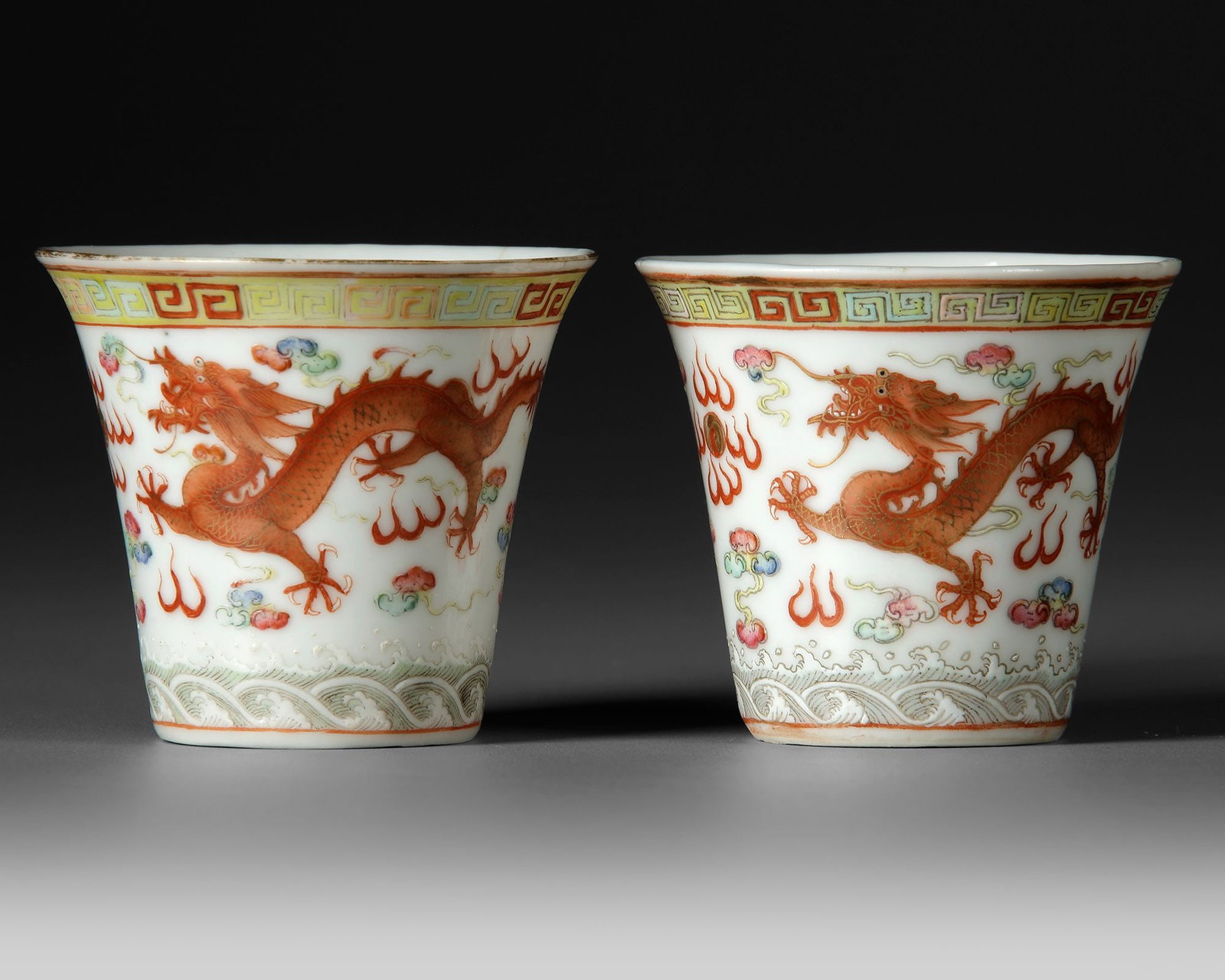 A PAIR OF FAMILLE ROSE â€?DRAGON AND PHOENIXâ€™ CUPS WITH, GUANGXU MARK AND OF THE PERIOD: A fine pair of Chinese porcelain cups, each painted in iron-red, famille rose enamels and gilt with a dynamic five-clawed dragon chasing the flaming pearl, accompanied by a phoenix and surrounded by a