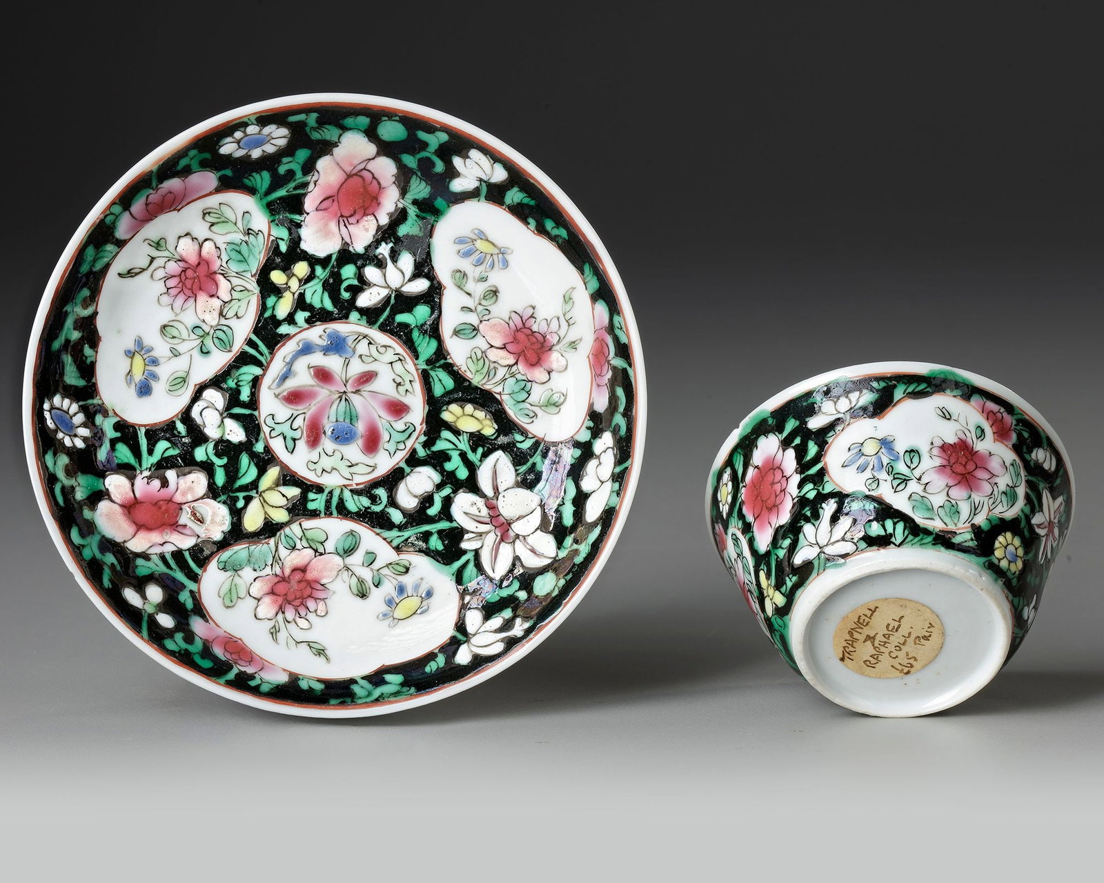 CHINESE FAMILLE ROSE CUP AND SAUCER, 18TH CENTURY: An elegant Chinese Famille Rose porcelain cup and saucer . Finely decorated with delicate floral medallions and scrolling foliage in soft pink, green, yellow, and blue enamels against a striking black