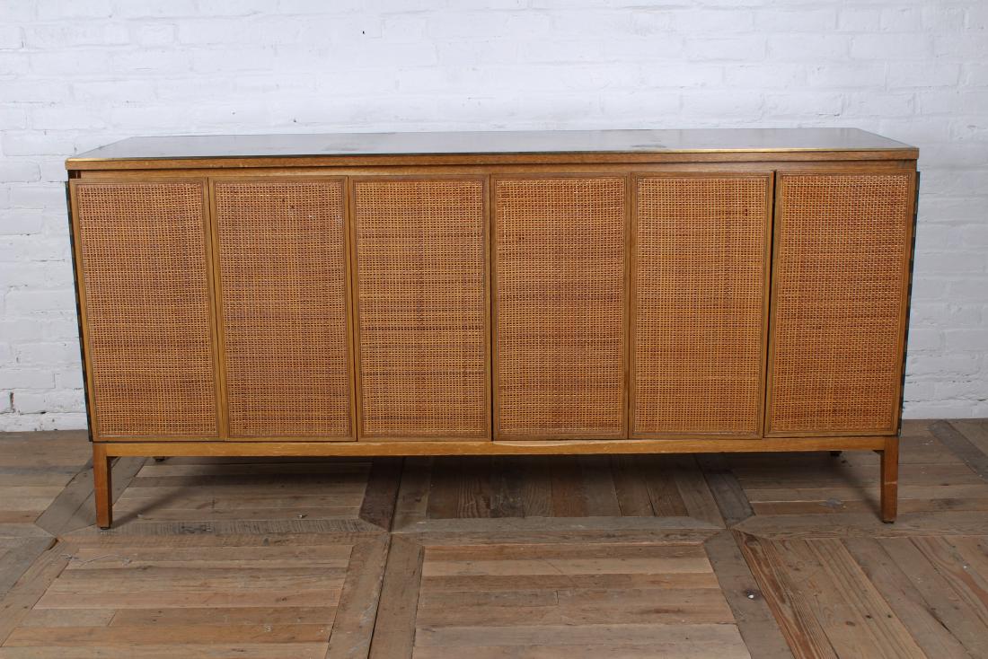 Paul McCobb for Calvin Sideboard/Credenza: Very good Paul McCobb for Calvin labeled side board/credenza having a bronze trimmed leather top over woven trifold doors and raised on tapered legs. Circa 1950. Good overall condition with some finis