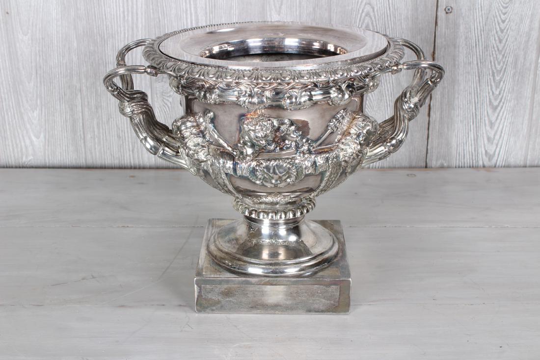 Silverplate Warwick Urn Style Wine Cooler: Very good English? Silver-plate Warwick urn style wine cooler with gadroon edge over twist handles and deep relief figural/bust mounts all raised on stepped socle. Size: 10 1/4" H x 12 1/2" W x 9 3/4"