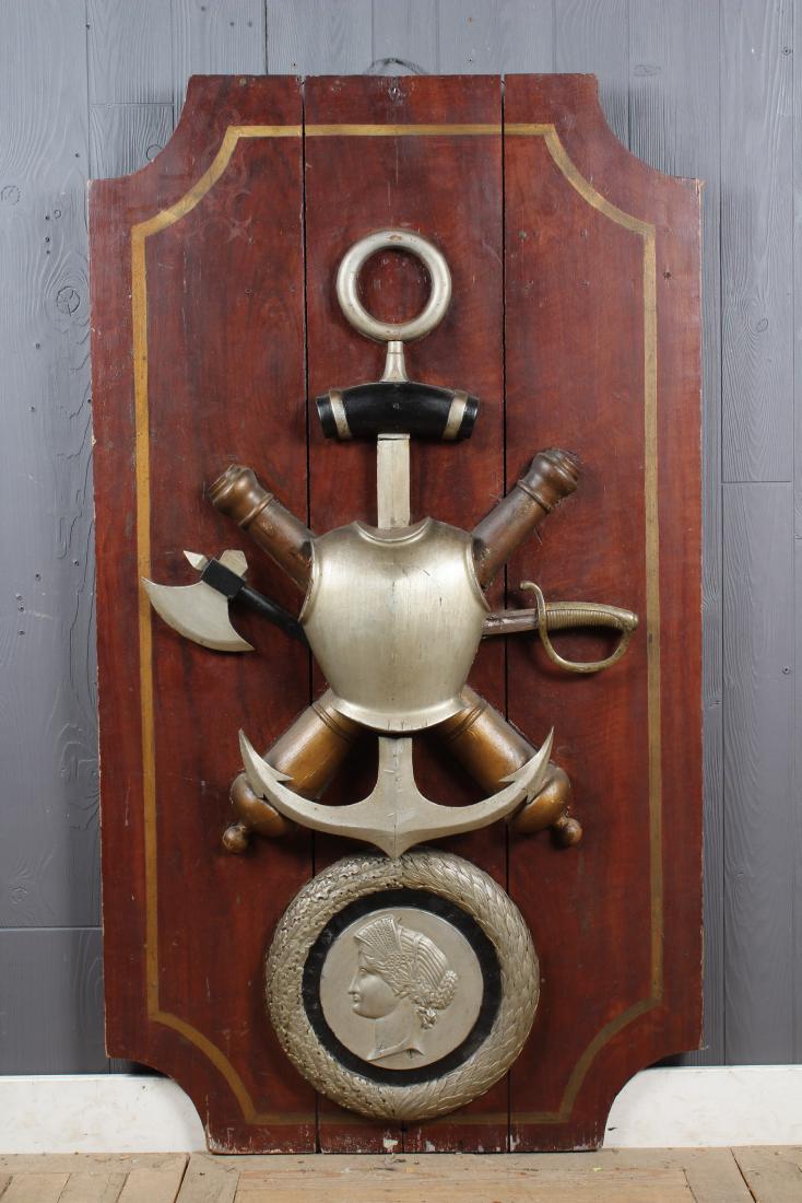 Large Carved and Painted Heraldic Naval Plaque: Large Carved and Painted Heraldic Naval Plaque. Bearing an armor breast plate, crossed cannons and and anchor over a circular wreath bearing the portrait of liberty. Size: 59.5" H x 33" W x 4.5" D