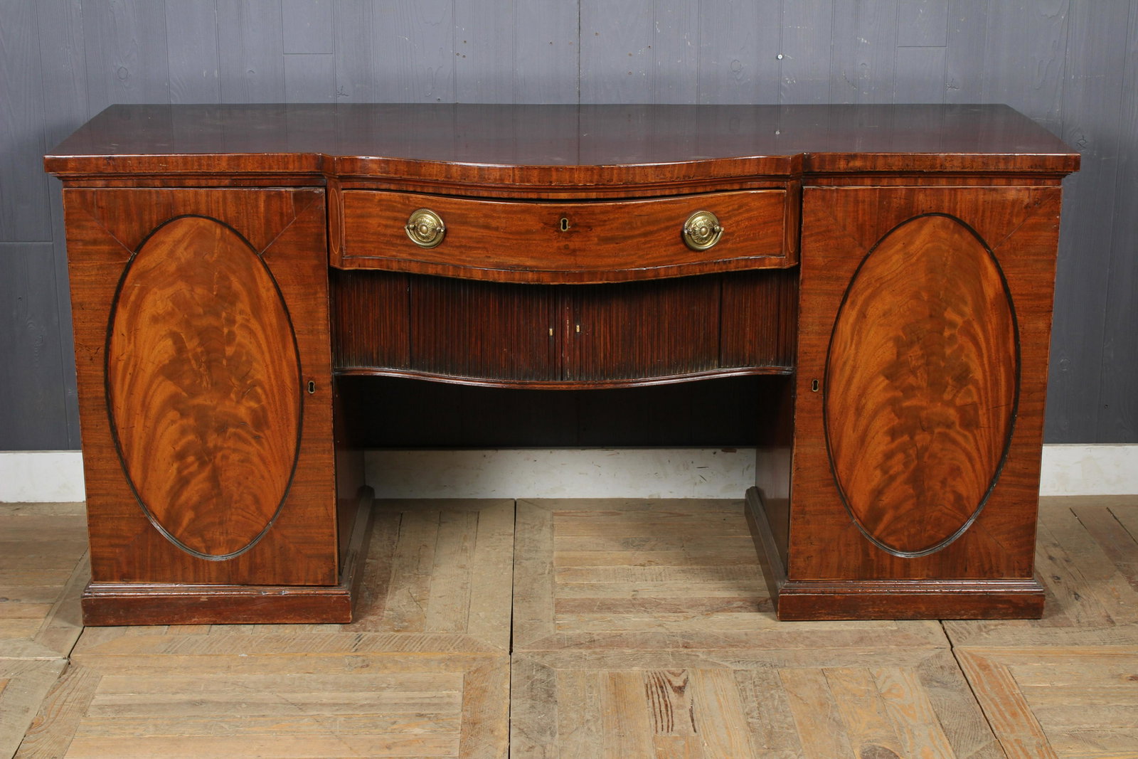 Georgian Style Bow Front Sideboard: Bow Front Sideboard, center drawer over tambour doors, flanked on both sides by panel doors with interior fitted drawers, small concealed door on side. Size: 33.5" H x 68" W x 27" D