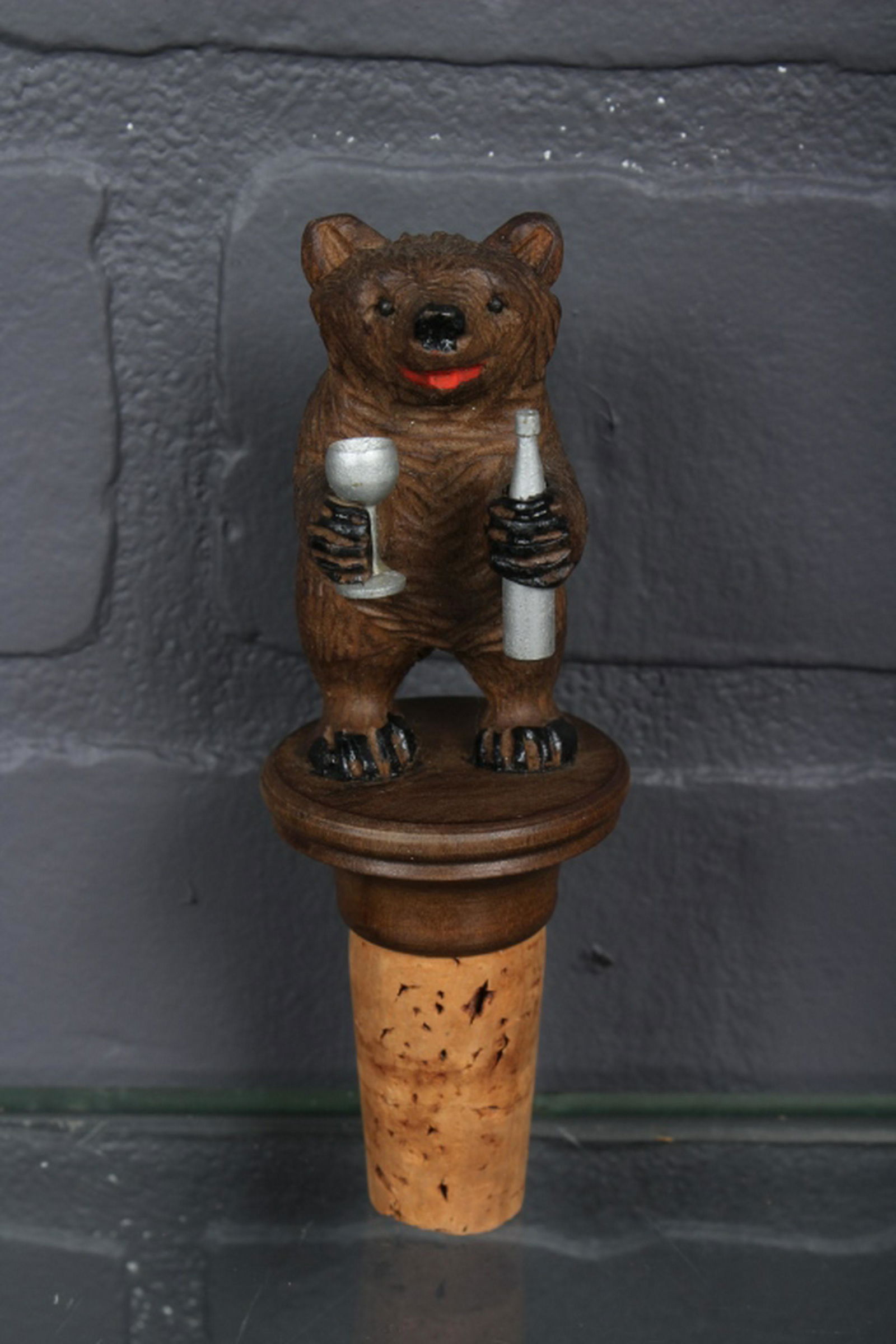 Carved Wood Bear Bottle Stopper: Carved Wood Bear Bottle Stopper, Anri or Anri type, bear is holding a glass and a bottle. Size: 4.5" H x 1.5" W x 1.5" D.