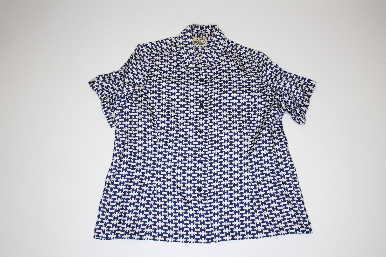 Hermes Paris Silk Short Sleeve Shirt: Hermes Paris Silk Short Sleeve Shirt, white and blue H monogram design, double breast pockets, labeled Hermes Sport Paris. Measures 15" shoulder to shoulder, 25" shoulder to hem.