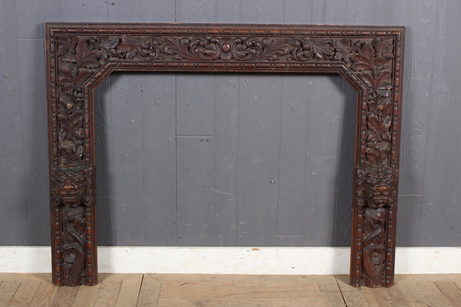 Heavy Relief Carved Wood Mantle: A late 19th century Victorian carved oak over mantle frame having lion face, oak and leaf carved decoration. Size: 39" H x 52" W x 5.5" D