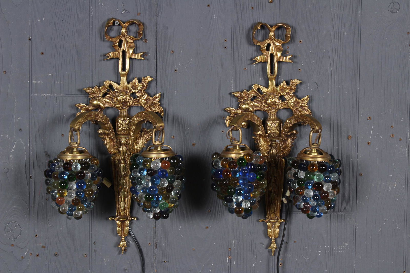 Pair French Regency Bronze Sconces: Pair Bronze and Colored Glass Wall Sconces, gilt bronze having bow and swag with floral and foliate design, each having two grape clusters of hanging colored glass bunches. Size: 18.5" H x 10.5" W x 5
