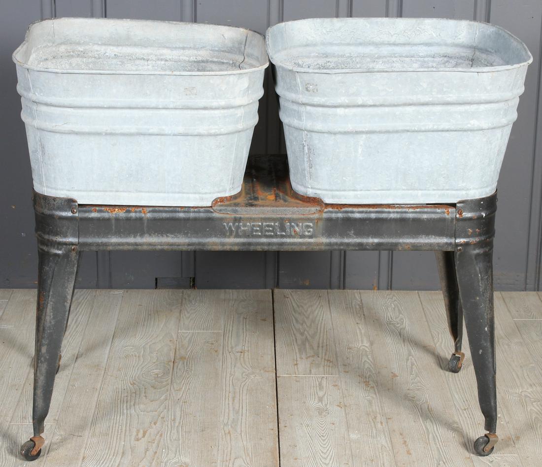 Wash Basins on Stand: A labeled Wheeling tub stand with two galvanized tubs supported on metal base. 33" x 40" x 18"
