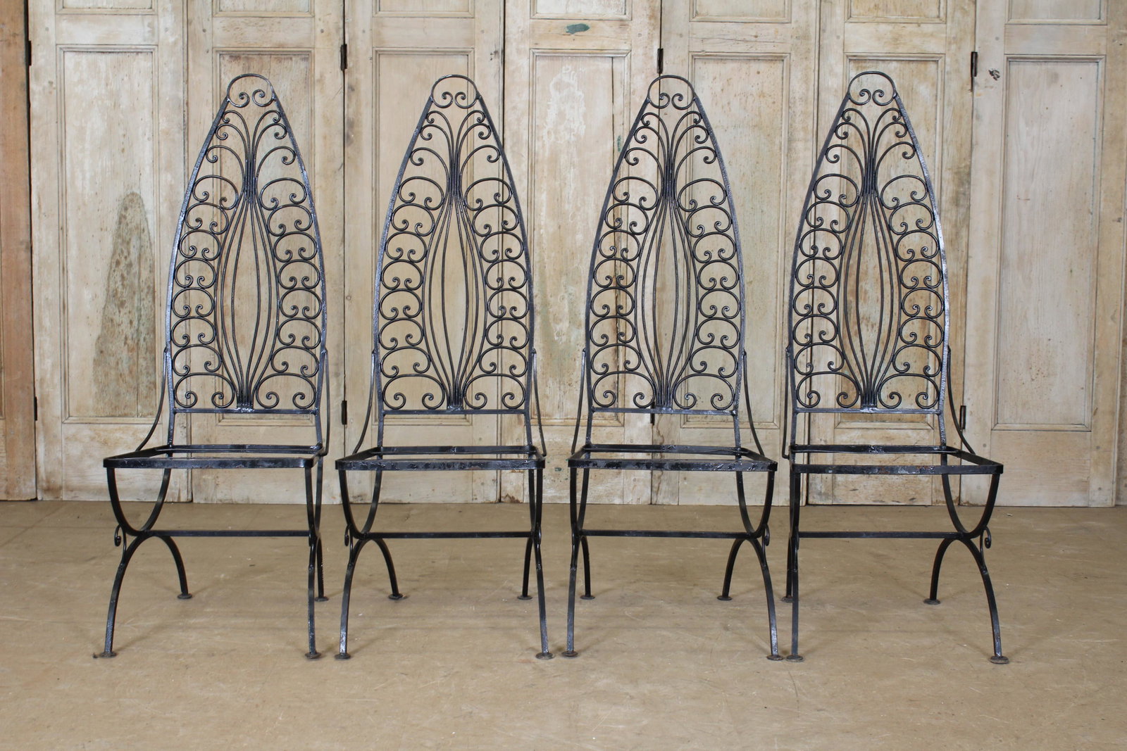 4 Peaked Back Wrought Iron Chairs: An interesting set of four vintage wrought iron garden chairs having stylized arched backs with scroll design. 49" x 17 1/2" x 21"