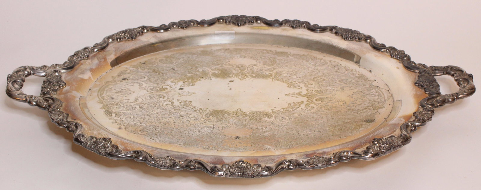 Large Silver Plated Double Handled Serving Platter: Large Silver Plated Double Handled Serving Tray, engraved foliate and scroll design, repousse border, footed, unmarked. Size: 3" H x 30.5" W x 20.5" D ***Please Note: This is an on-site online auction