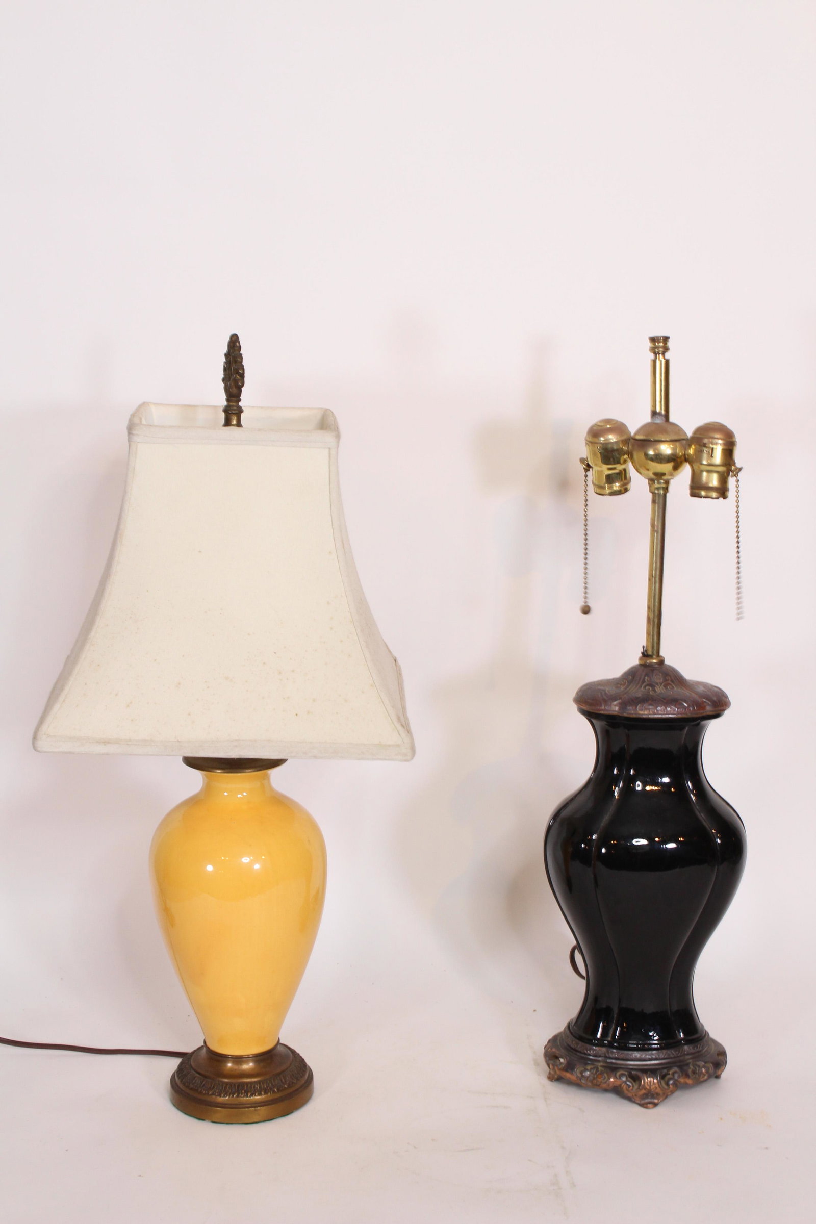 Two Decorative Ceramic Table Lamps: Two ceramic table lamps including, Black ceramic table lamp, double socket and a yellow ceramic table lamp with cloth shade. ***Please Note: This is an on-site online auction with specific Pick up ter