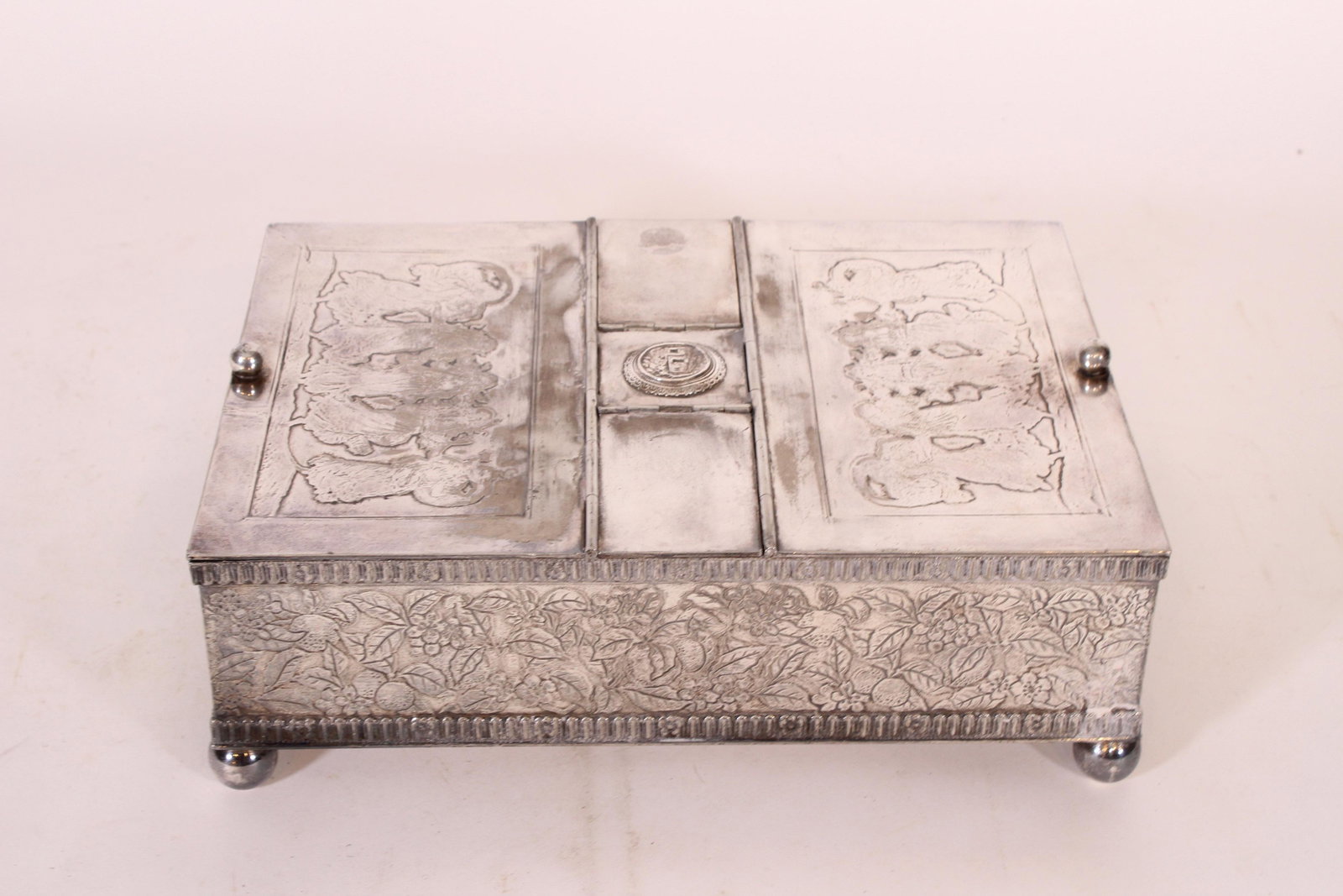 Meriden Silver Plated Humidor Box: Meriden Silver Plated Humidor Box, figural top, floral and foliate design, ball feet, hinged lids, one center hinged lid broken, hallmarked on bottom Meriden B Company 32, USA. Size: 4" H x 11.5" W x 
