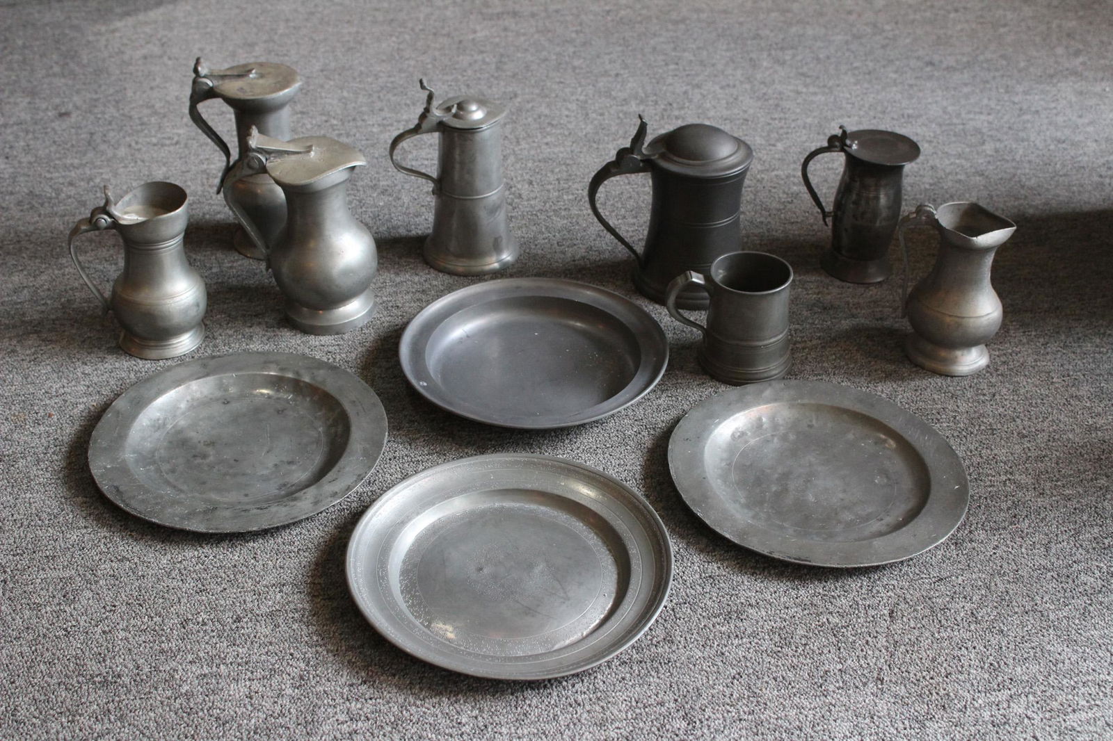 Lot of 12 Pieces of Antique Pewter: A lot of 12 pieces of antique pewter including tankards and plates.Size: Largest 7" ***Please Note: This is an on-site online auction with specific Pick up terms and conditions. Pick up day is schedul