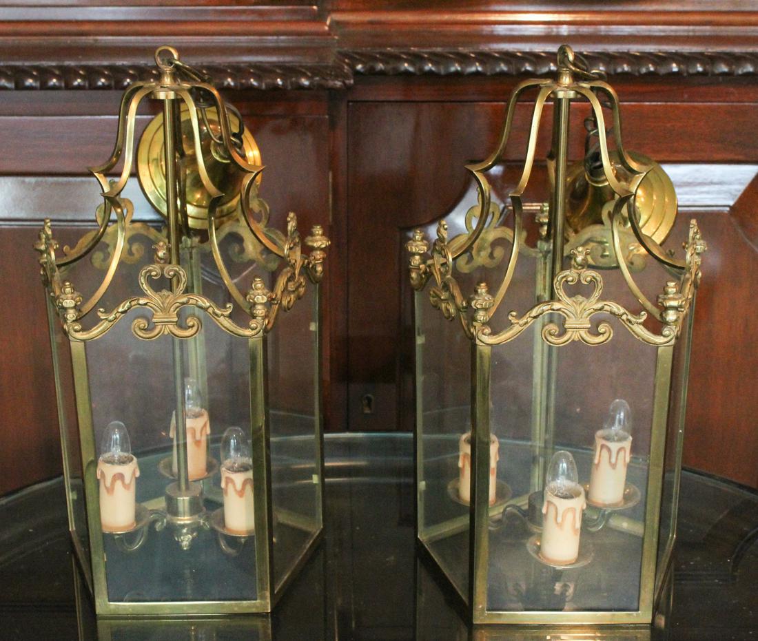 Pair of Hanging Brass Hall Lanterns: A pair of hanging brass lanterns in the French taste with glass paneled sides. Size: 16"Hx 8"W x 8"D ***Please Note: This is an on-site online auction with specific Pick up terms and conditions. Pick 