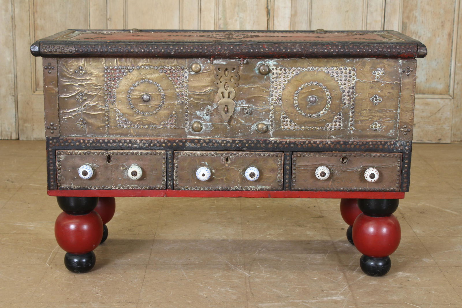Brass Clad Trousseau Chest: A late 19th Century Anglo Indian brass clad and nail head decorated trunk having lift top over three drawers with porcelain knobs all raised on bolbous turned feet. Size: 28"H x 43"W x 18"D