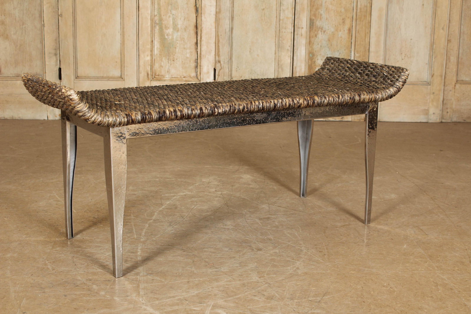 Bench: A bench having shaped woven grass seat supported by polished metal tapered legs. Size: 22"H x 49.5"W x 18"D