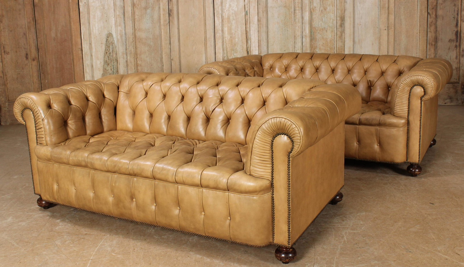 Pair of Leather Chesterfield Couches: A pair of leather Chesterfield couches each having tufted backs and seats with rolled arms and raised on turned feet. Size: 29"H x 72"W x 36"D