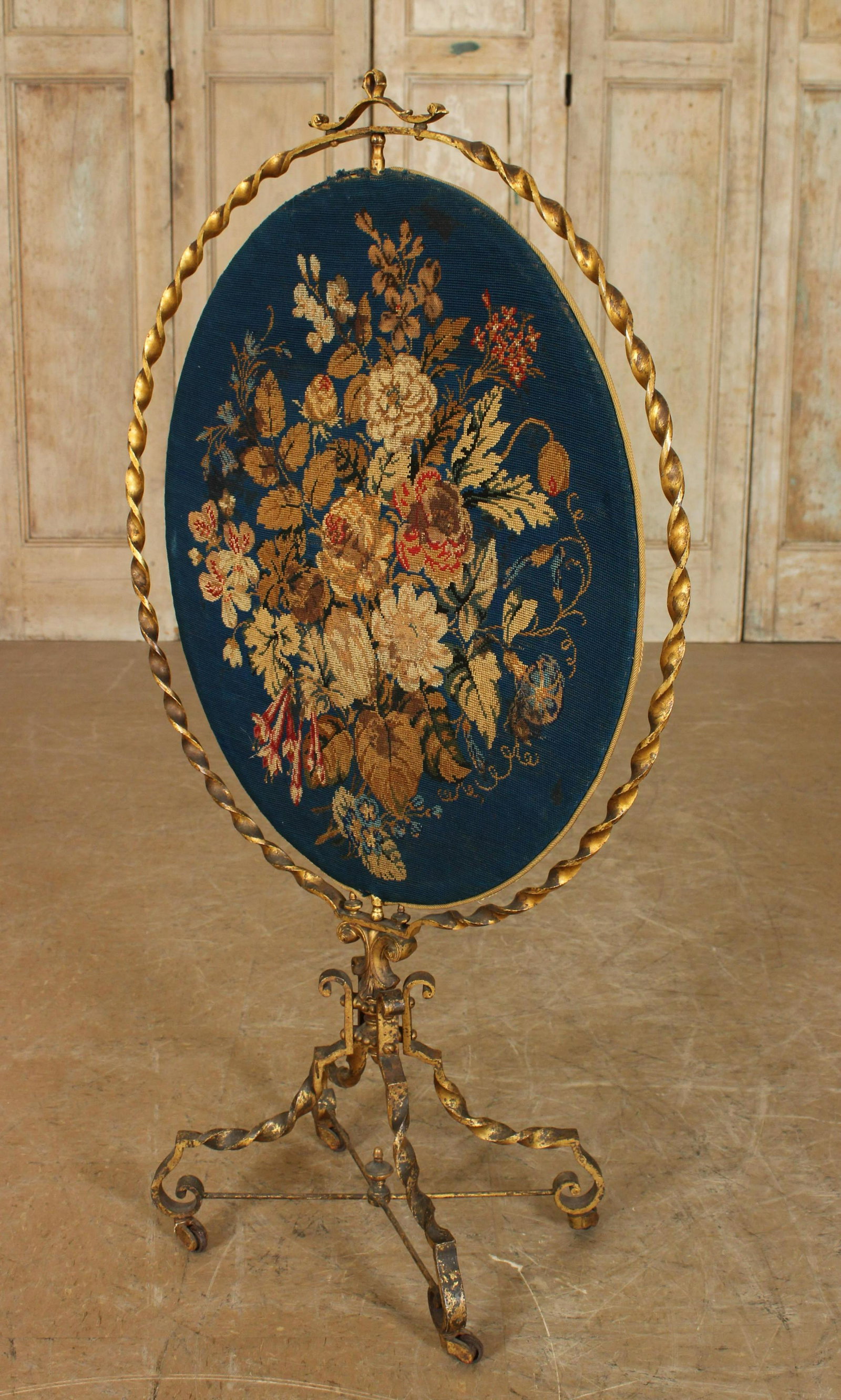 Needlepoint Wrought Iron Fire Screen: Needlepoint Wrought Iron Fire Screen, floral needlepoint in a twist form frame, supported on twist form legs and casters. Size: 44" H x 14.5" W x11.5" D