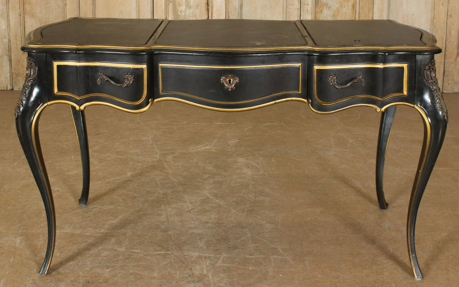 French Louis XV Style Drexel Writing Desk: French Louis XV Style Drexel Writing Desk, or Library desk, painted black and gilt, with bronze ormolu mountings, center drawer flanked by two short drawers, labeled. 29.5" H x 51" W x 26.5" D