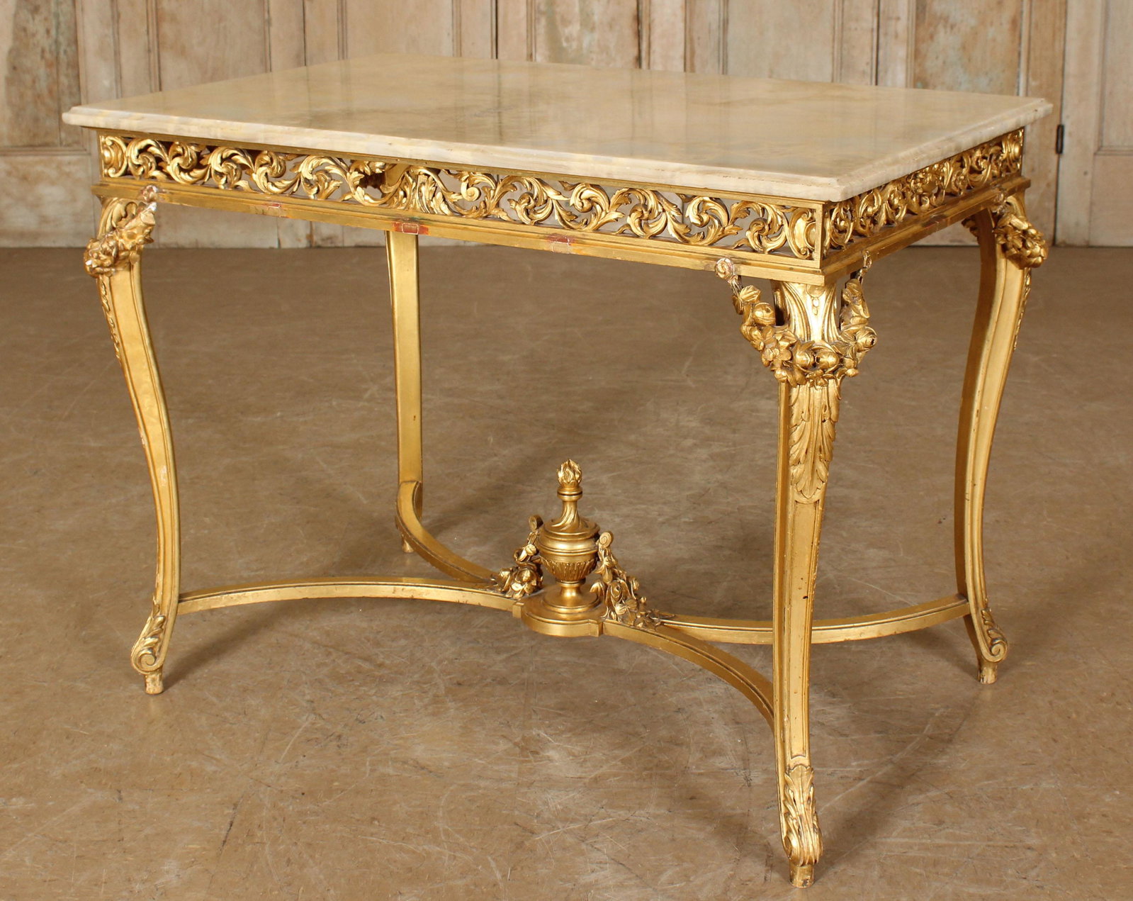 French Carved Gilt Wood and Marble Top Table: French Carved Gilt Wood and Marble Top Table, labeled Morel Goyer Lille, applied swag decoration, x-form stretcher with urn form center. Size: 29" H x 39" W x 26.25" D