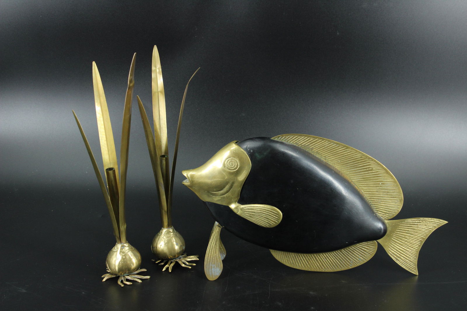 Mid C. Modern Brass and Wood Fish and Candlesticks: Mid C. Modern Brass and Wood Fish and Candlesticks, ebonized wood with brass head and fins, and a pair of foliate candle holders. Size: 8.75"H x 3.5"W x 15.5"D