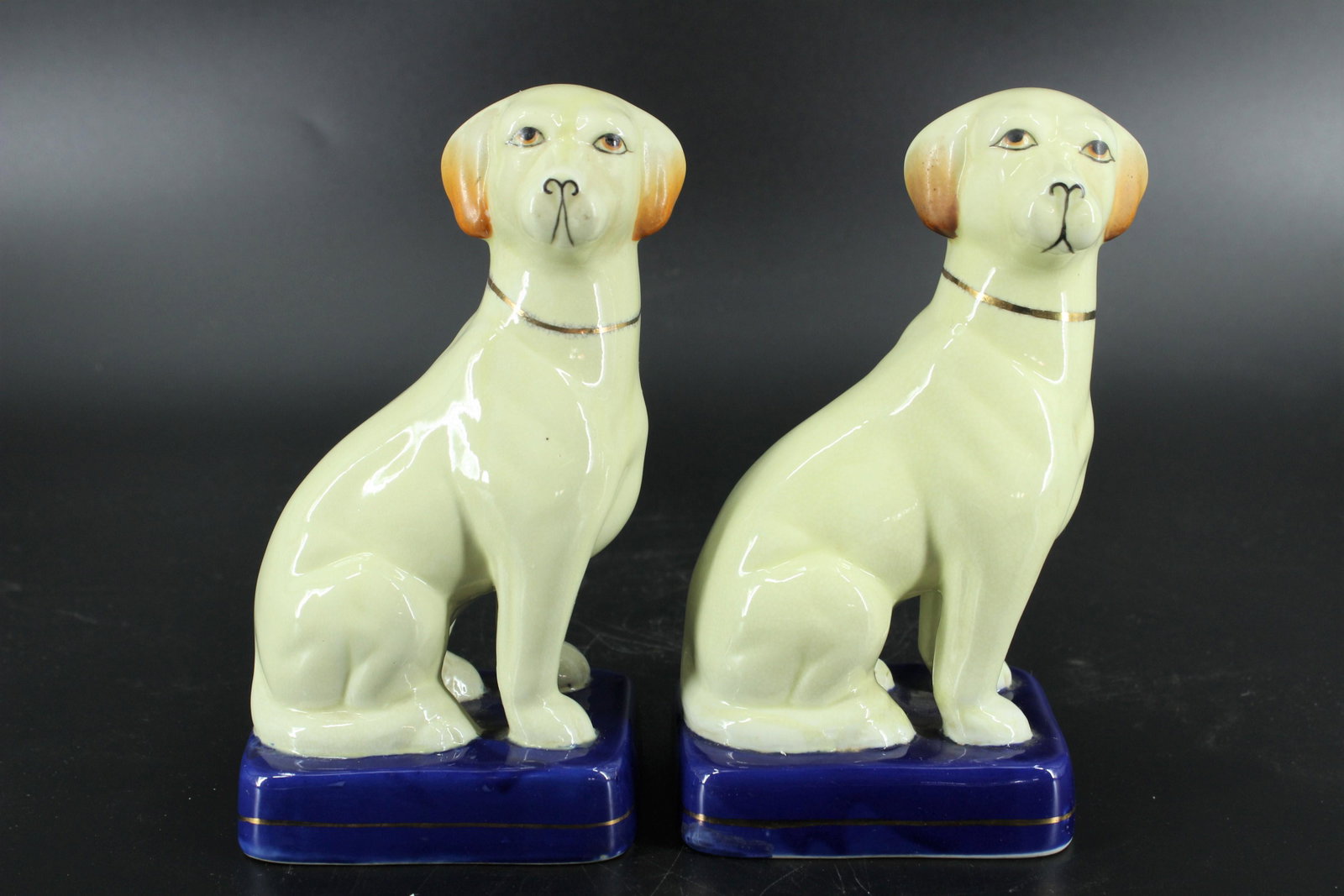 Pair Ceramic Staffordshire Style Dog Figurines: Pair Ceramic Staffordshire Style Dog Figurines, painted blue bases, one hallmarked on bottom with a Crown above an L. Size: 7.5"H x 4"W x 4"D