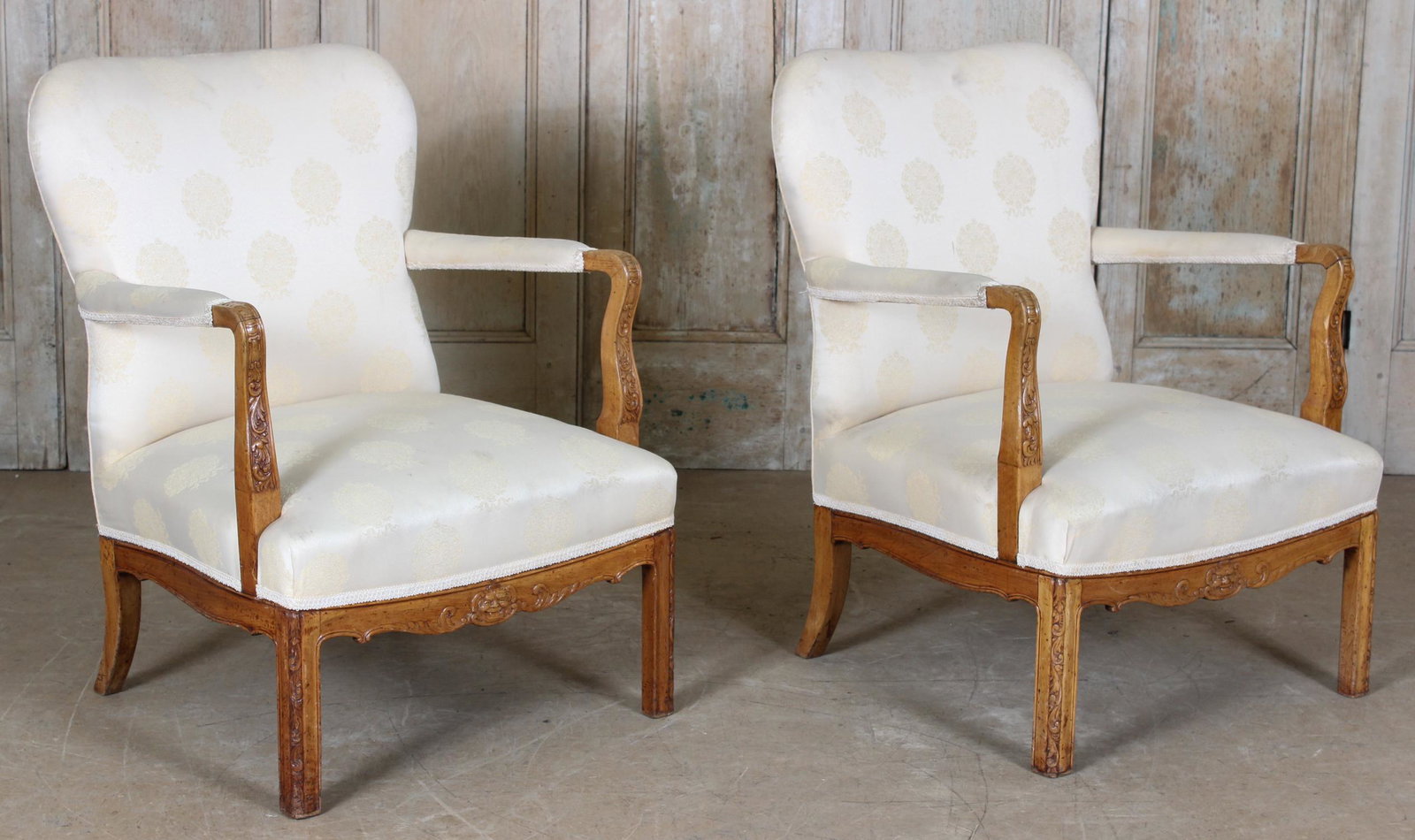19th C. Continental Directoire Open Arm Chairs: A pair of continental late 19th early 20th Century upholstery open arm chairs having mask carved and decorated apron. Size: 34.5" H x 25.5" W x 27.5" D