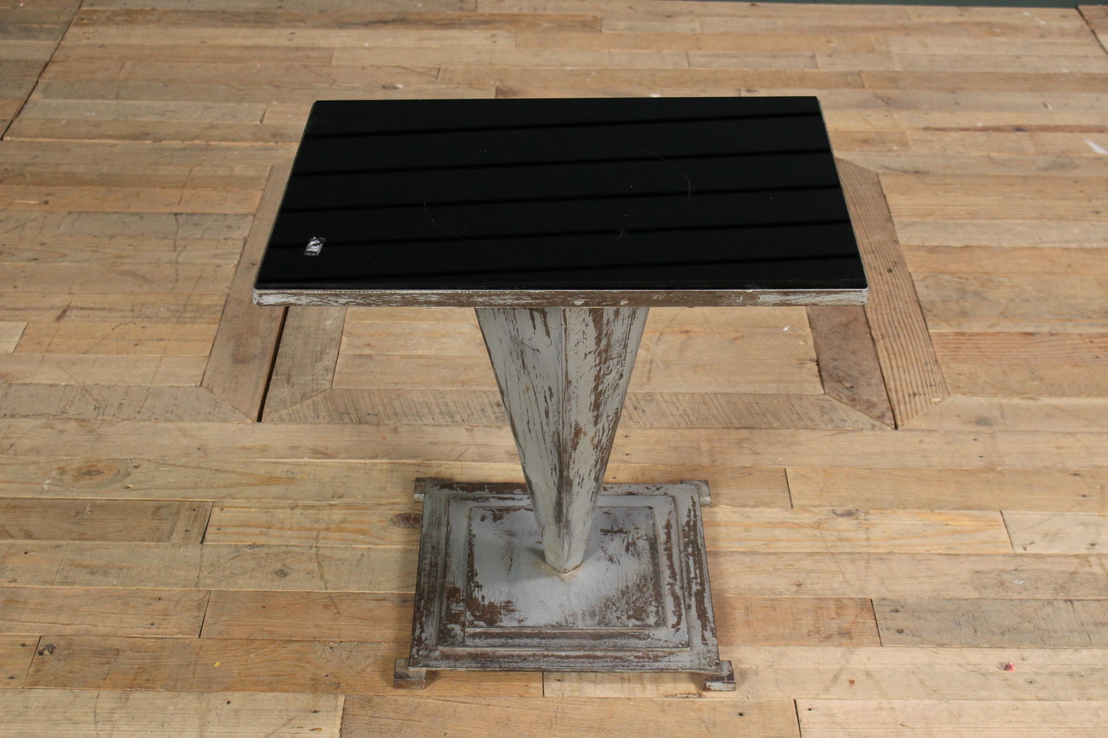An Art Deco Metal Side Table: An Art Deco Metal Side Table having an inset black glass top, supported on reverse conical pedestal and stepped base. Size: 19" H x 20" W x 15" D.