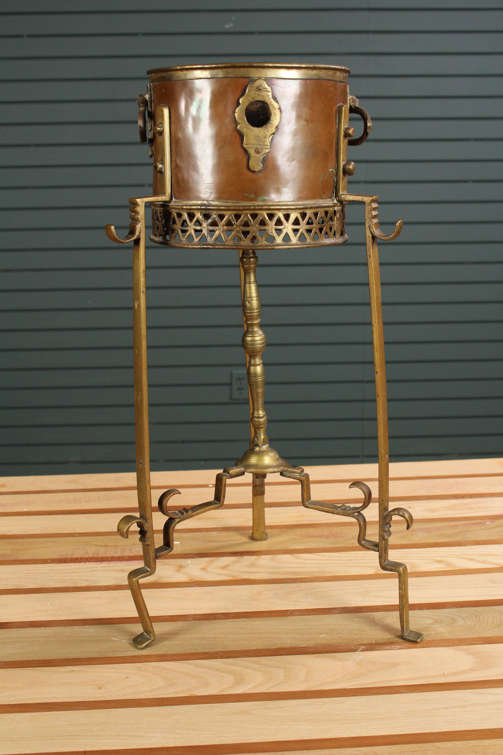 Regency Style Brass and Copper Bucket on Stand: Regency Style Brass and Copper Bucket on Stand, having drop rings and reticulated triton. Size: 25.5" H x 12" W x 12" D.