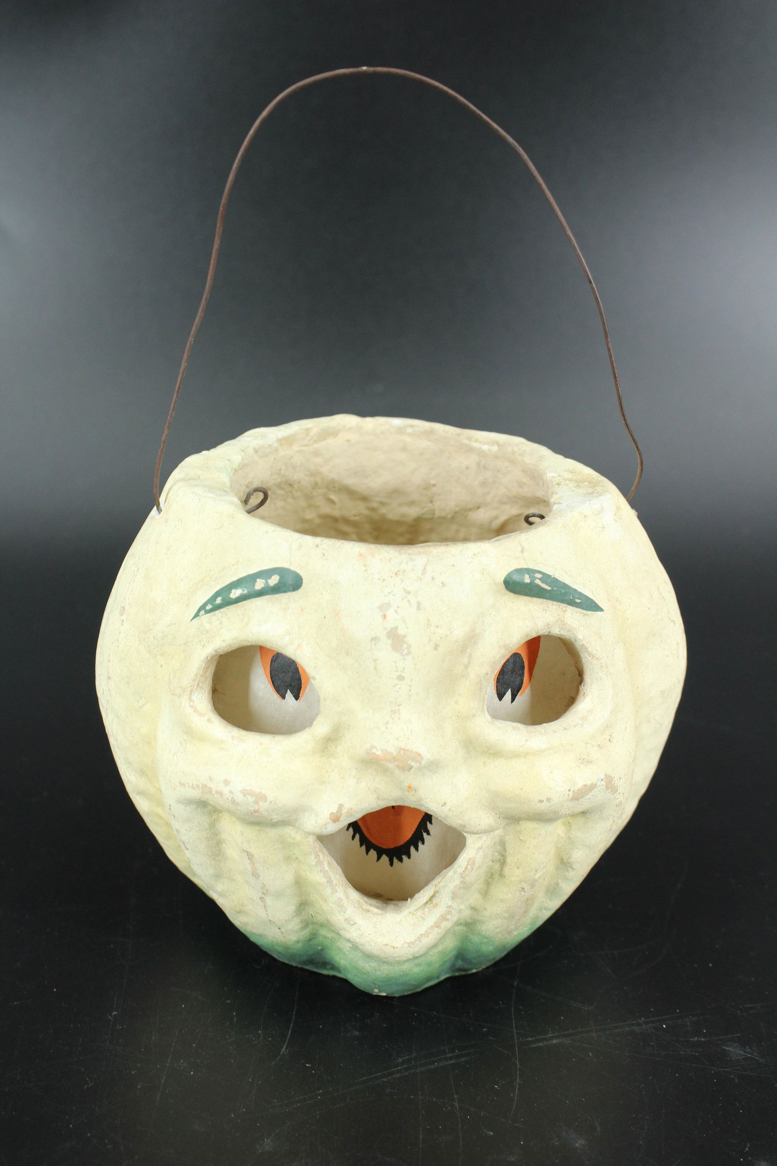 Vintage Composition White Jack-O-Lantern: Vintage Composition White Jack-O-Lantern, painted white and green pumpkin head, wire handle, printed paper insert. Size: 5.5" H x 6.5" W x 5.5" D.