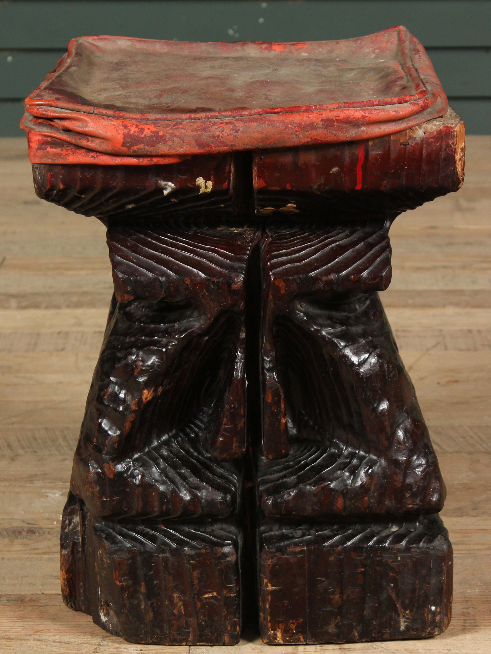 Witco Carved Wood Stool: A Witco style footstool with a chip carved wood base, possibly a head, and a vinyl cushion. Size: 16" H x 12" W x 12" D