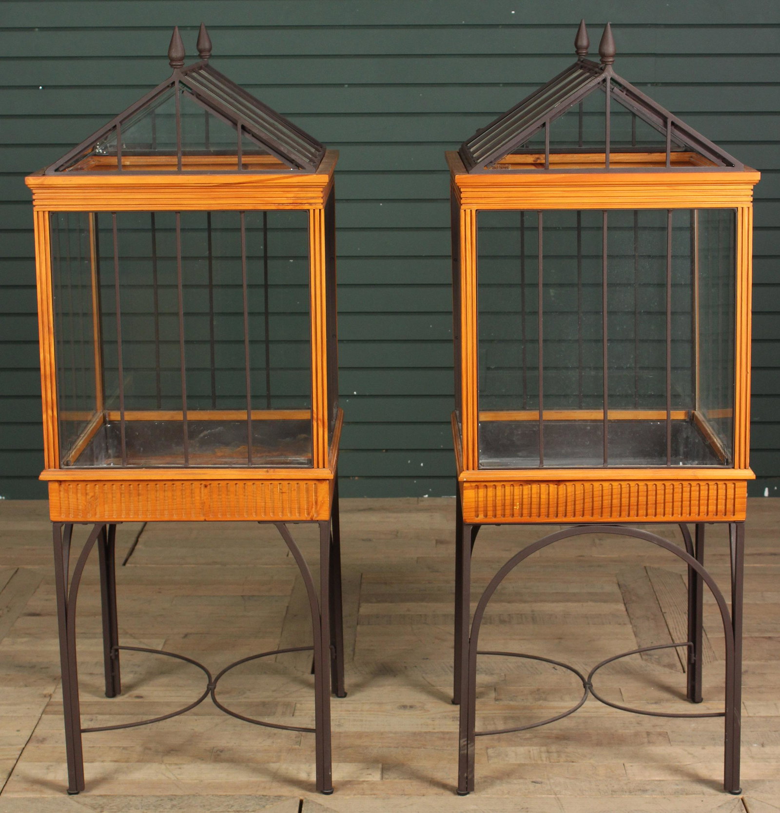 Pair of Terrariums on Stands: A pair of terrariums or Wardian Cases each having glass, metal and wood framed enclosures resting on metal base. Size: 52" H x 20" W x 20" D