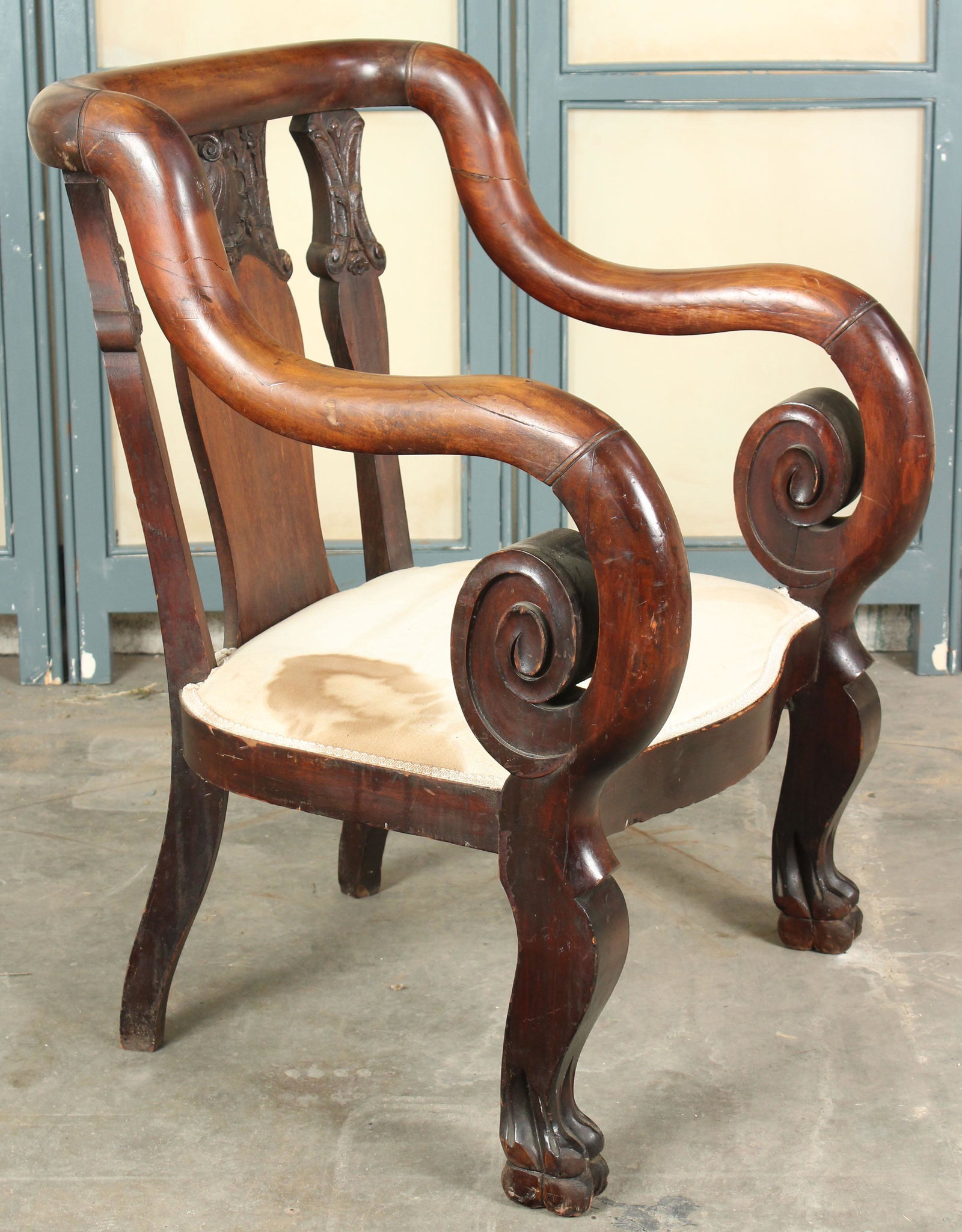 American Empire Serpentine Scroll Armchair: A unique armchair having a wide carved back that serpentines to scroll arms, resting on carved paw feet. Size: 36.5" H x 28" W x 27" D Provenance: Production of â€œDickinson”