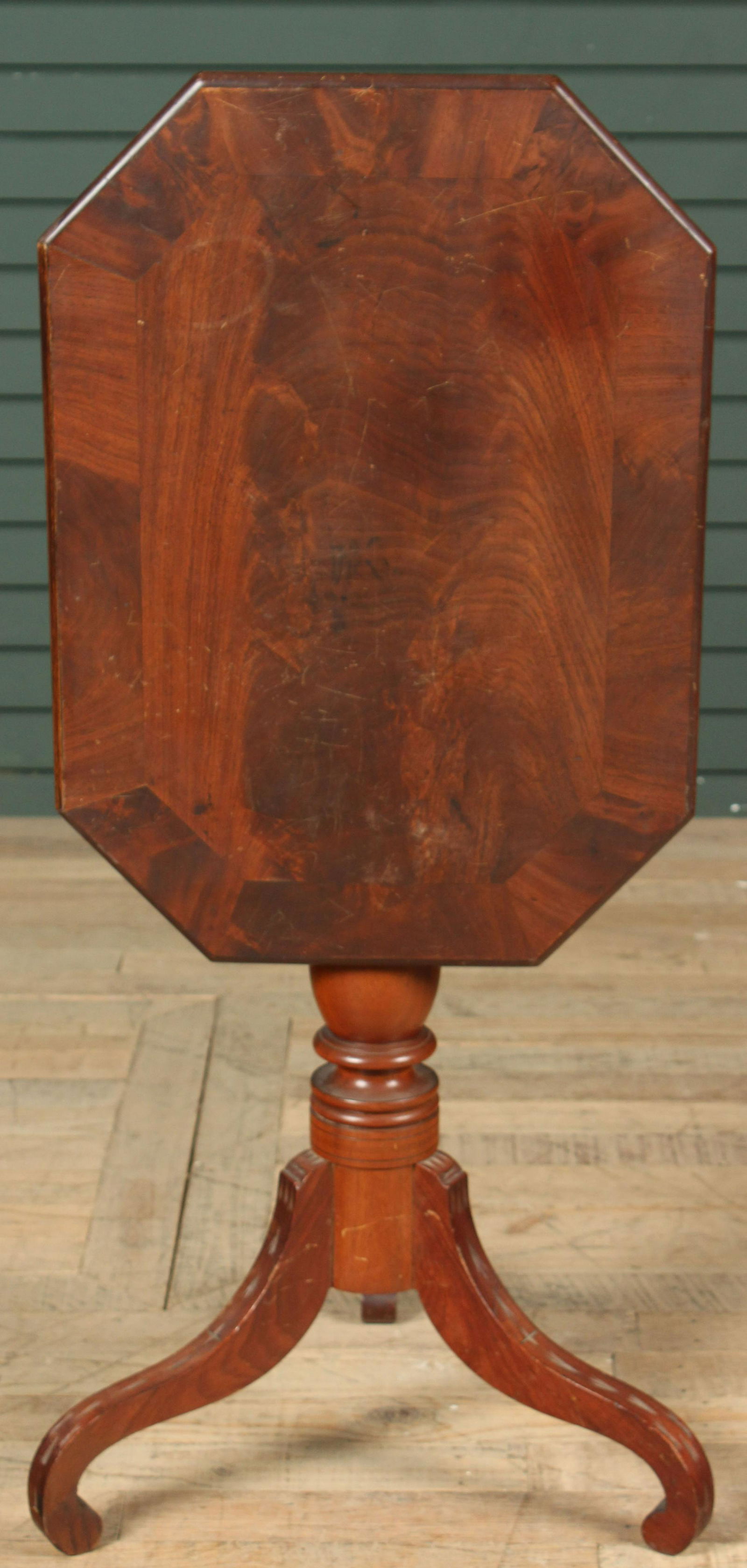 Antique Octagonal Tilt Top Tea Table: An antique tilt top table having an elongated octagonal top resting on a turned column and three shaped feet. Size: 41.5" H x 19.5" W x 17" D Provenance: Production of â€œDickinson”