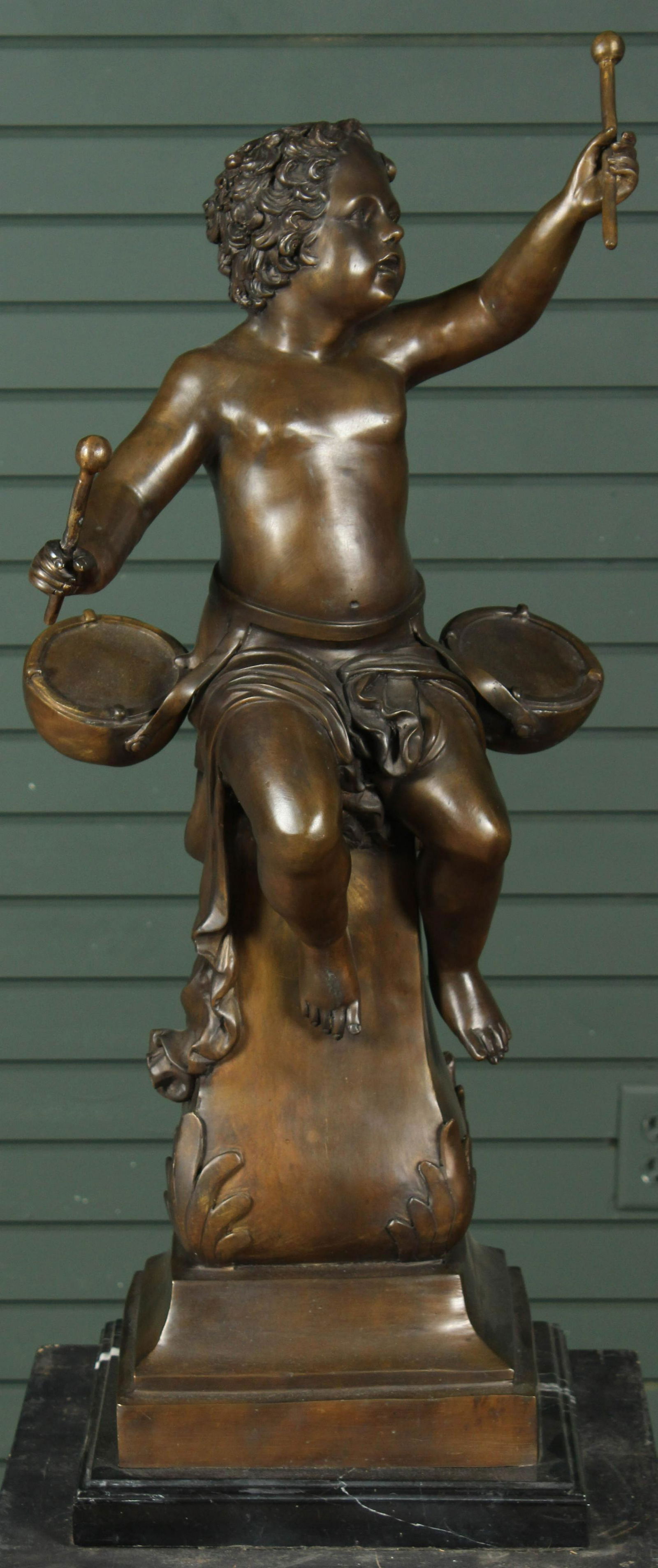 Figural Bronze Putto Drummer: A bronze sculpture of a drumming putto resting on a marble base. Size: 34.5" H x 13" W x 14" D