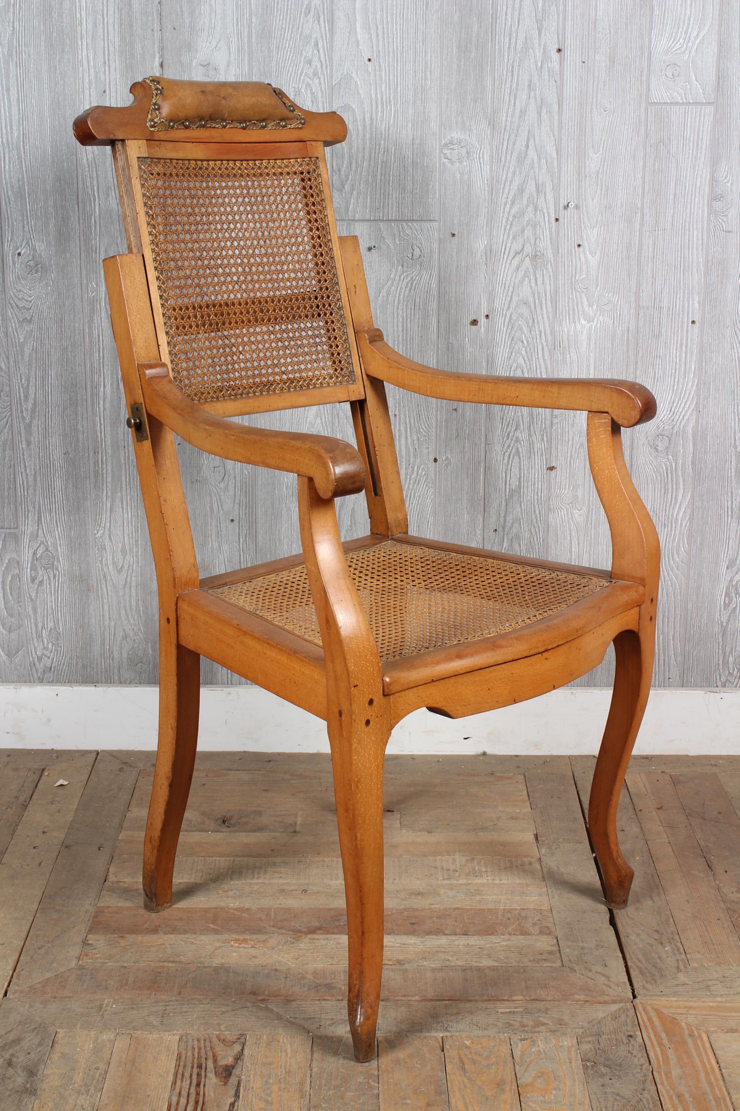 Antique Caned Barber Chair: A 19th century barbers chair with adjustable seat back with leather head rest over caned panel. The caned seat framed by open arms. Size: 42" H x 22.5" W x 24" D