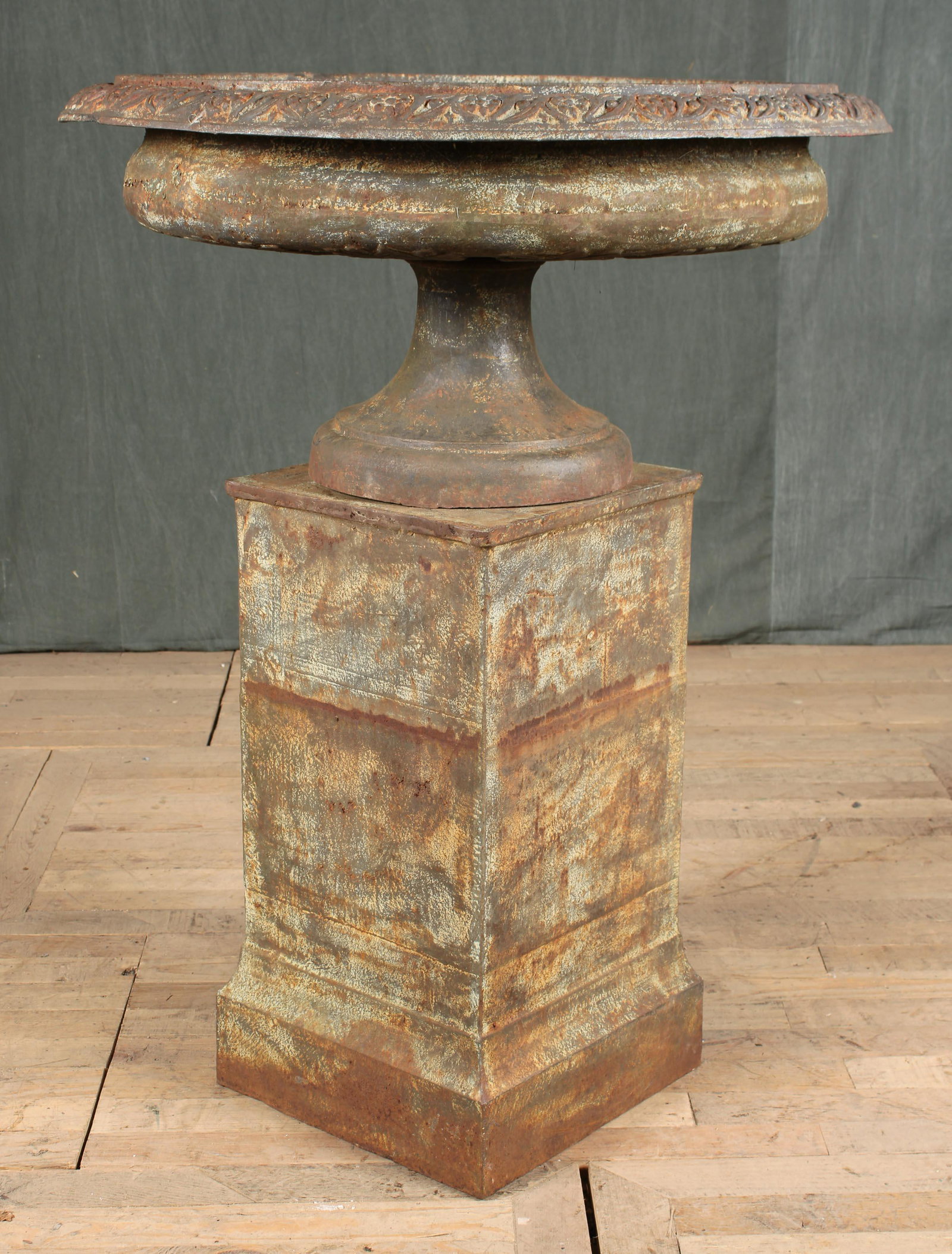 Large Scale Classical Form Cast Iron Urn: A large cast iron classical form shallow garden urn having vine and berry decorated rim and stepped base all raised on a pedestal. Size: 45"H x 34"Dia.