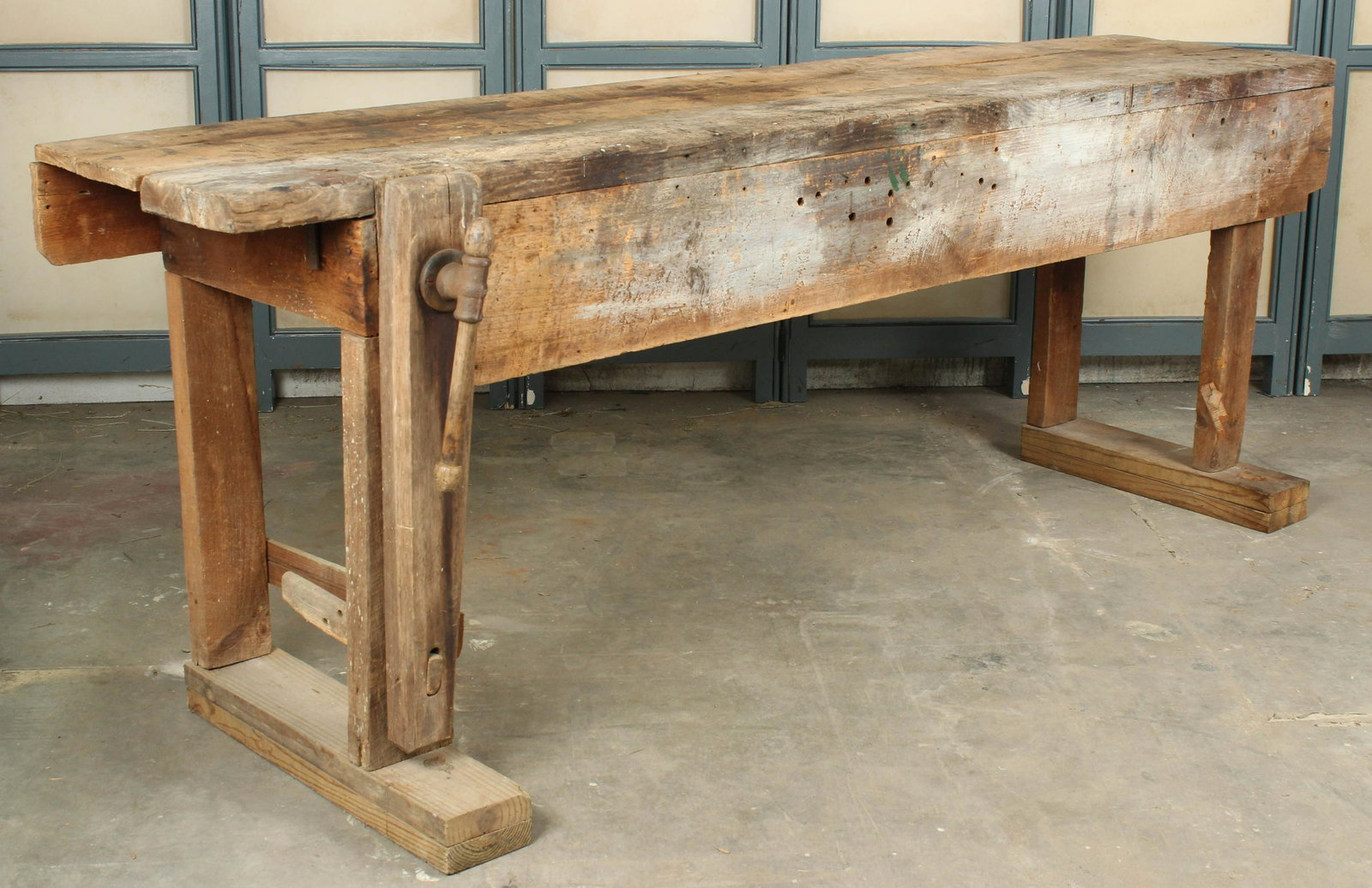 Antique Carpenters Bench: An antique carpenters bench having a plank top and apron, supported on timber legs and feet; having a fitted wood vise running down the length of the left leg. Size: 35" H x 96" W x 26" D