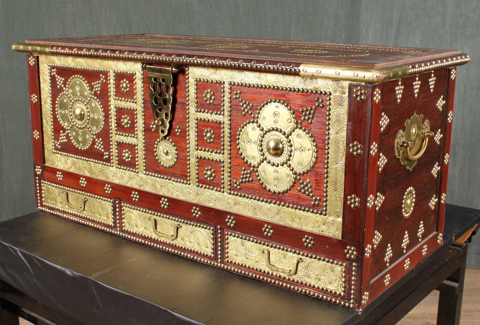 Brass Decorated Campaign Style Trunk: A campaign style brass decorated trunk having overall ball head and punch decoration including the front of three drawers. Size: 17"H x 38.5"W x 17.5"D