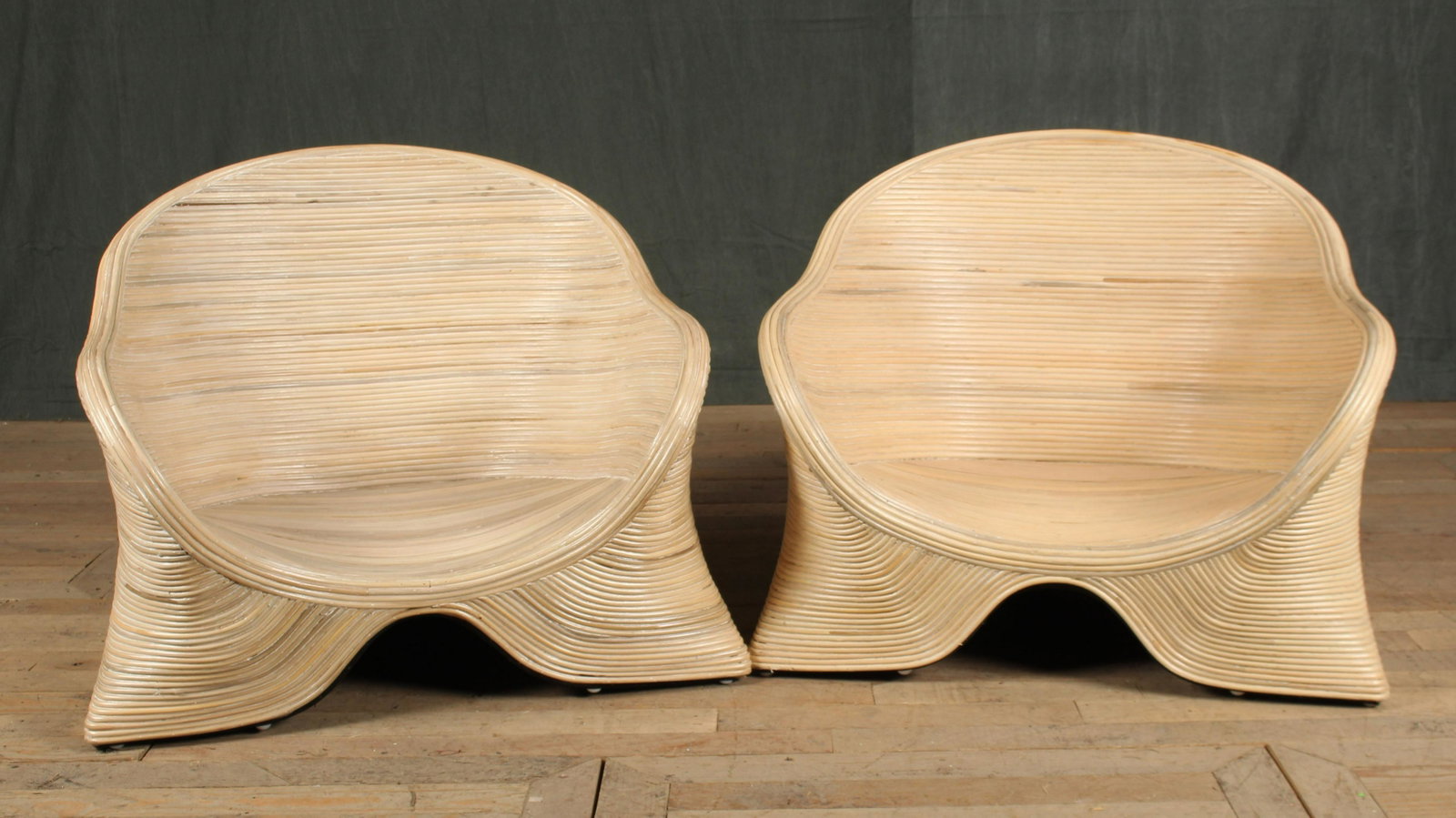 Pair Pencil Reed Low Slung Lounge Chairs: A stylish pair of Pencil Reed club chairs or low lounge chairs each having barrel backs and flared arms. IMO Betty Cobunpue. Size: 25.5" H x 30" W x 28" D