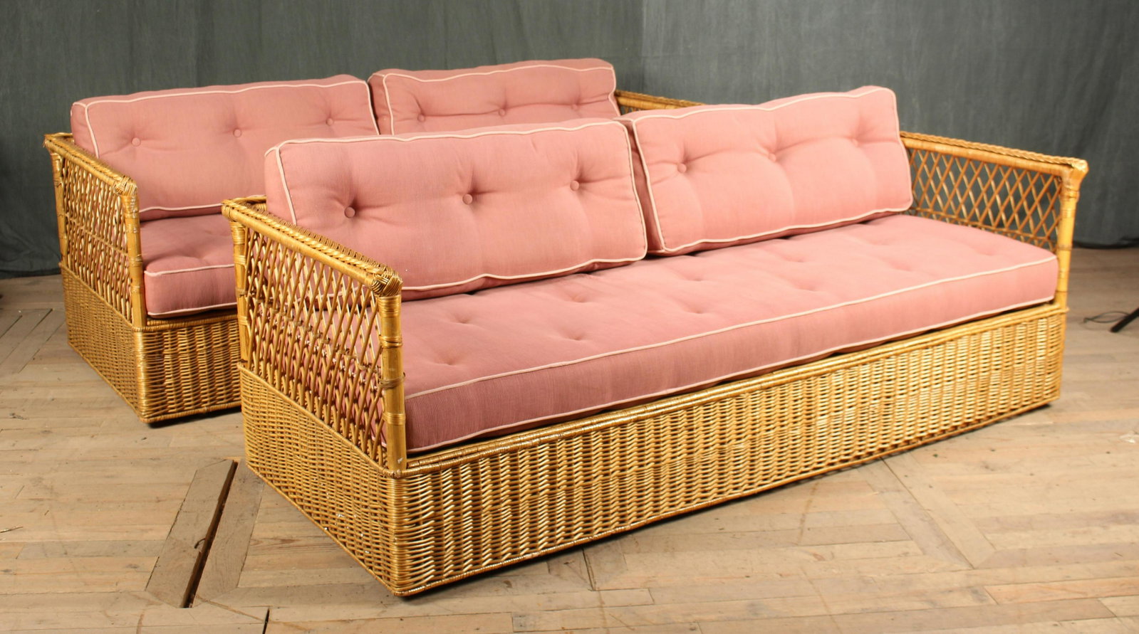 Pair Labeled McGuire Wicker Sofas: A pair of labeled McGuire wicker sofas each having trellis design back and sides framing loose back and seat cushions. Size: 26" x 77.5" x 32"