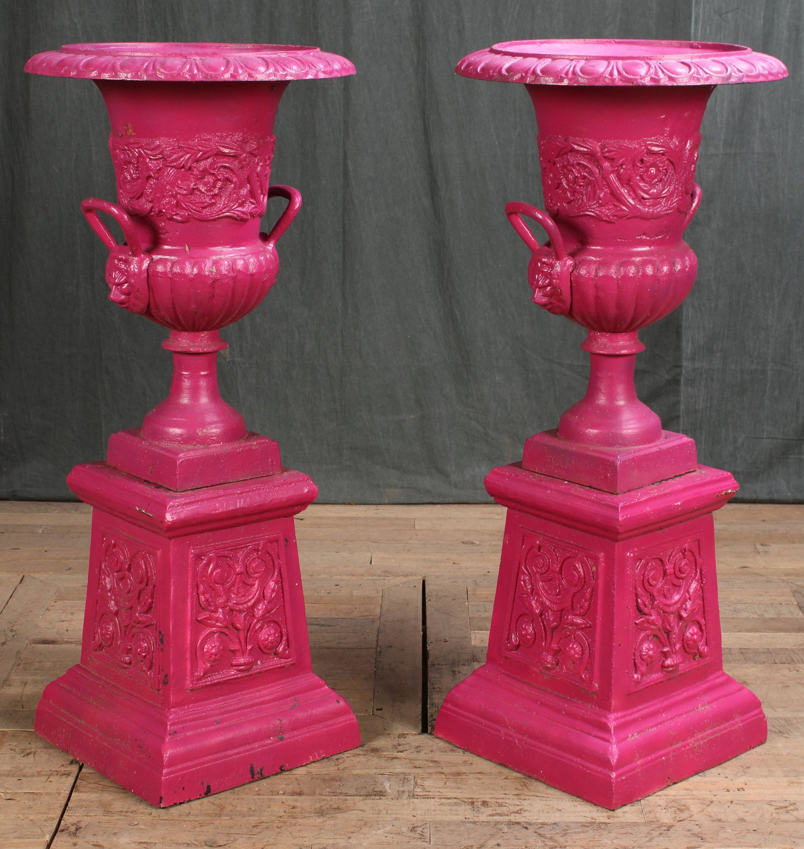 Fun Pair Cast Iron Campana Form Garden Urns: A good pair of cast iron garden urns of the campana form having lion form handles and leaf and scroll decorations. All raised on pedestals. Size: 37"H x 18"Dia.