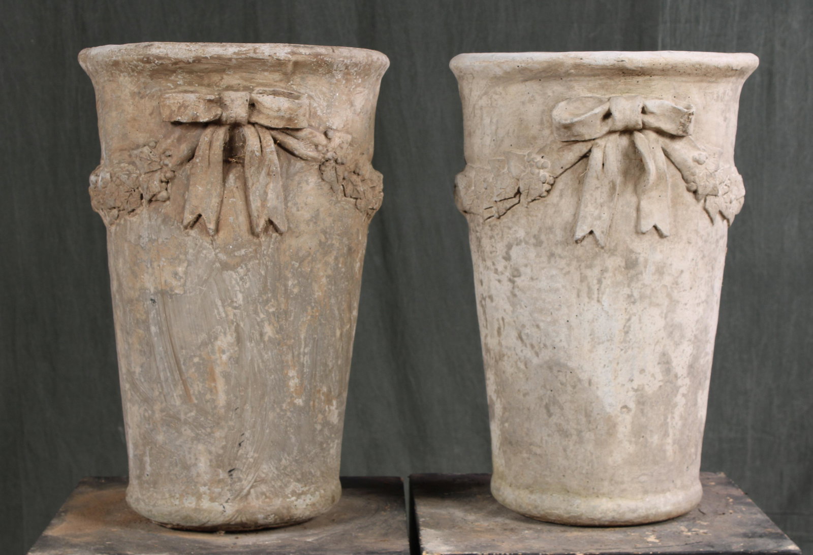 Pair Beaker Form Cast Stone Urns: A pair of cast stone beaker form garden urns having bow and draped garland decoration. Size: 21"H x 13.5"Dia.