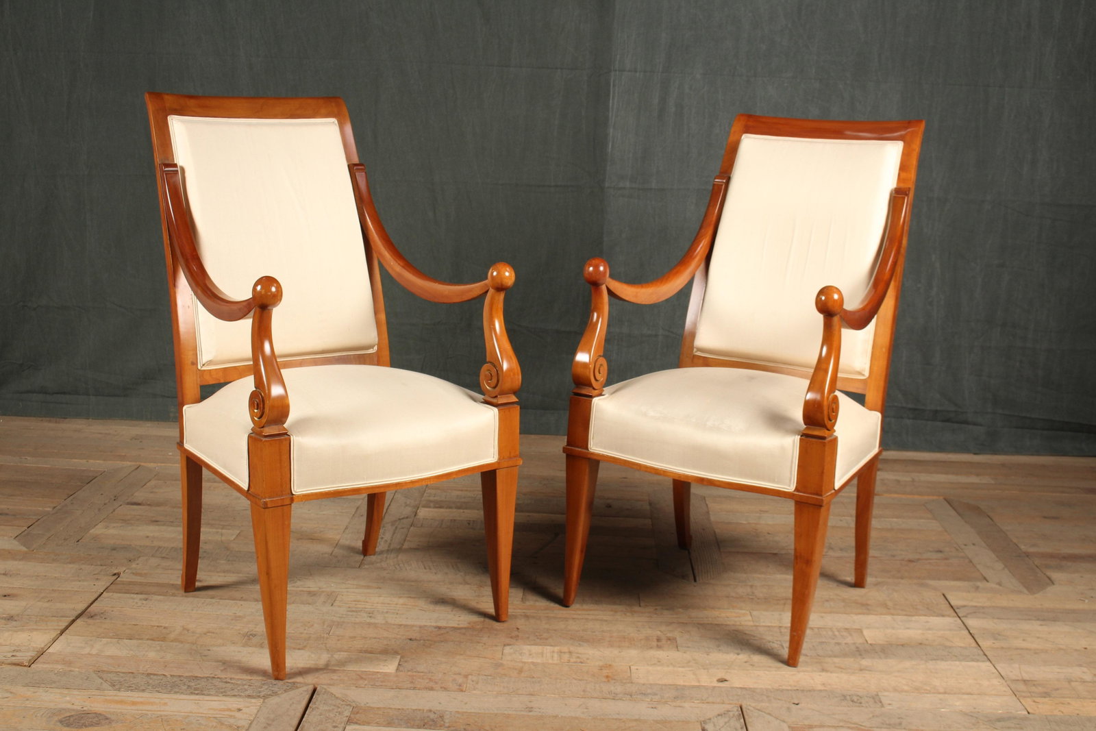 IMO Andre Arbus Armchairs: A pair of French early 20th century chairs in the style of Andre Arbus having upholstered back and seat framed y down swept arms with ball finials and scroll decoration. Size: 41"H x 22"W x 20"D