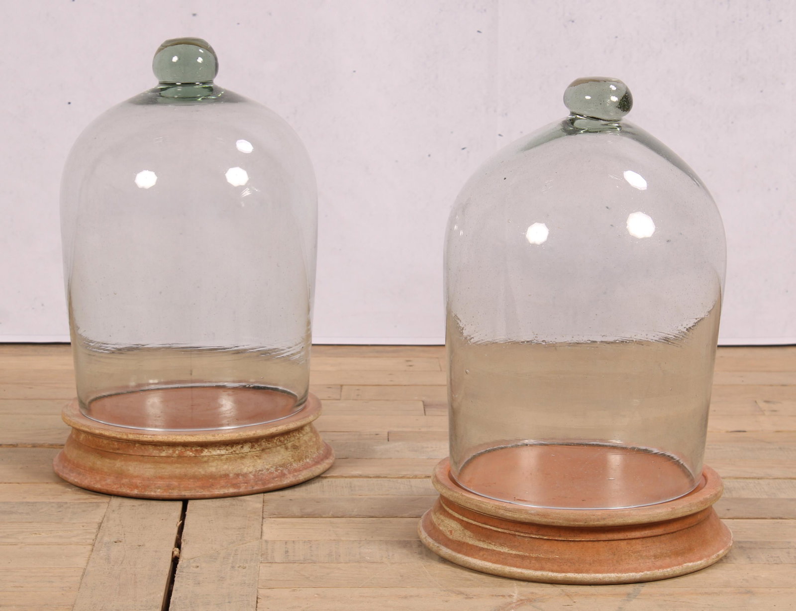 set of 2 Glass Cloches on Terracotta Bases: A near pair of domed glass cloches resting on terracotta raised bases. Size: 19"H x 12"Dia.