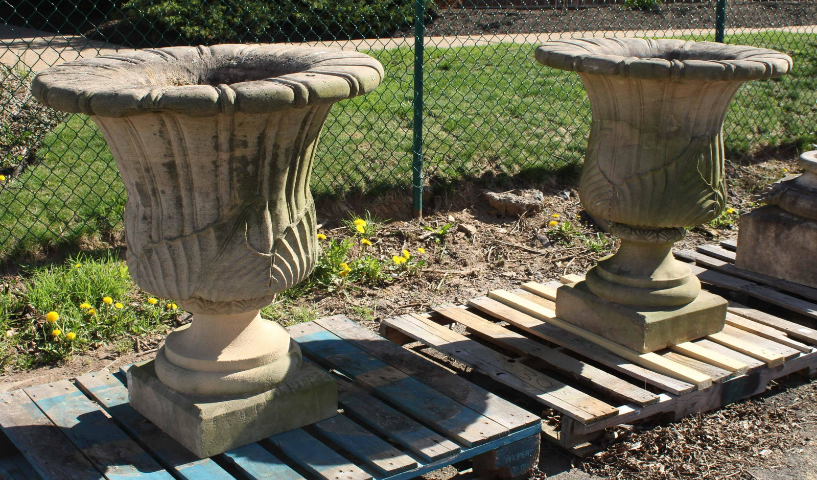 Monumental Carved Sandstone Urns: Classical fluted urns on square base in carved sandstone. Note: 1 urn split horizontally, as photographed. Measured: 37.5"T x 32.5" Dia.