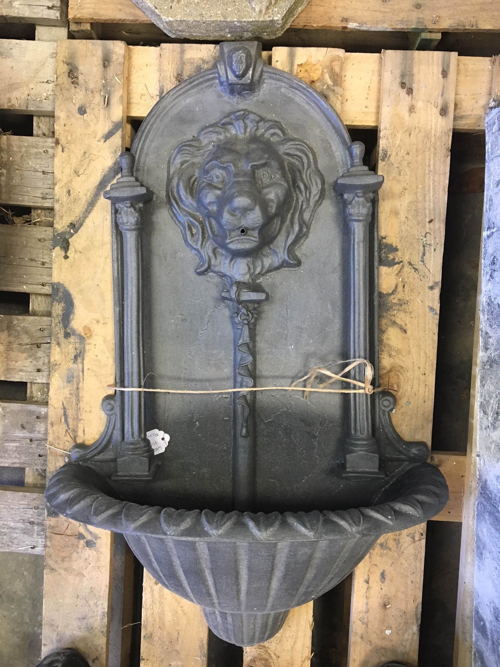 Lion Wall Fountain In English Lead: A good English cast lead wall mounted garden fountain having lion head mask framed by columns all above a demilune basin. One column is detached from backing. Size: 34"H x 20.5"W x 10"D
