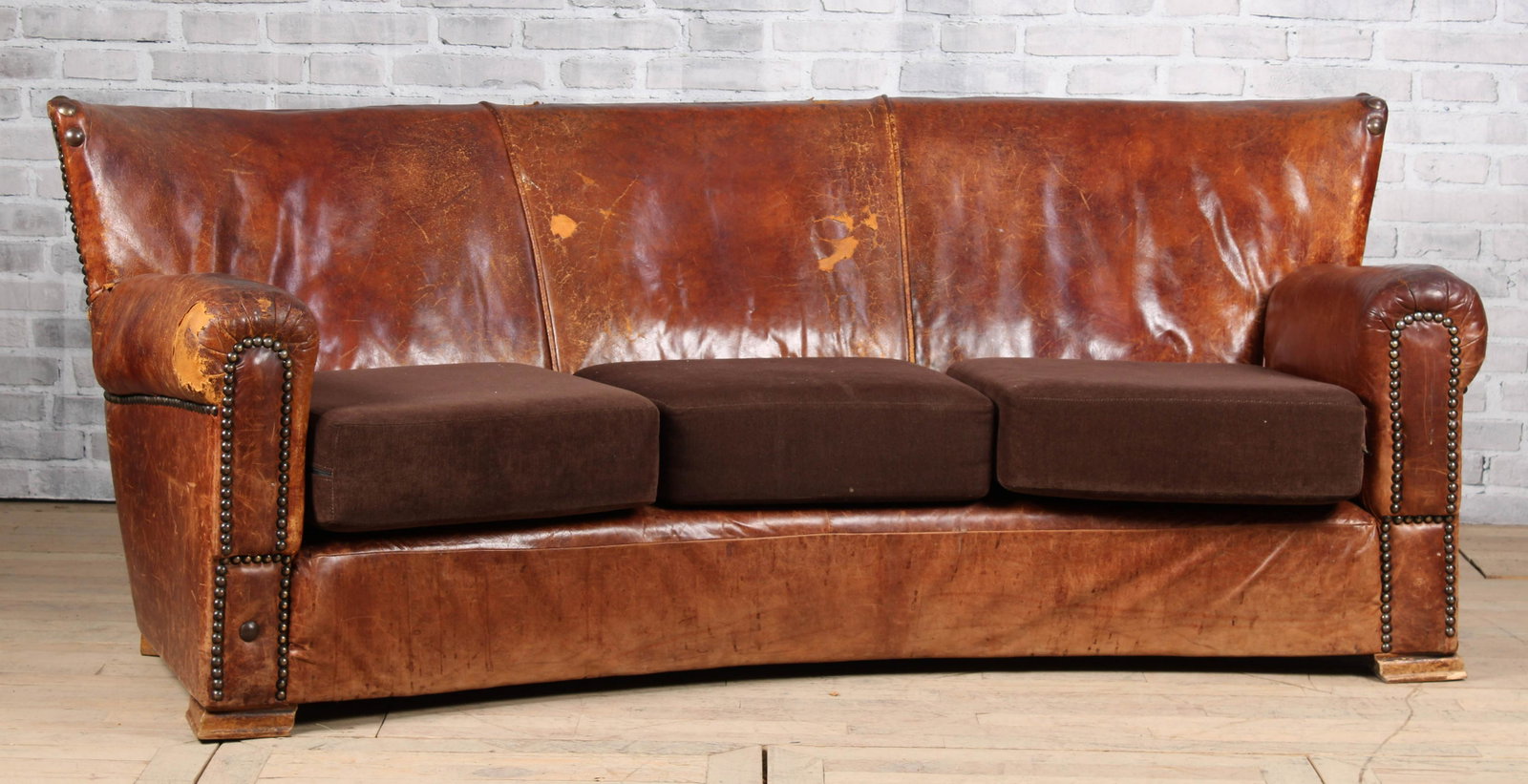 Belgian Leather Sofa: A good Belgian early to mid 20th curved back leather sofa with loose cushion seat and nail head decoration. Size: 33"H x 80"W x 40"D